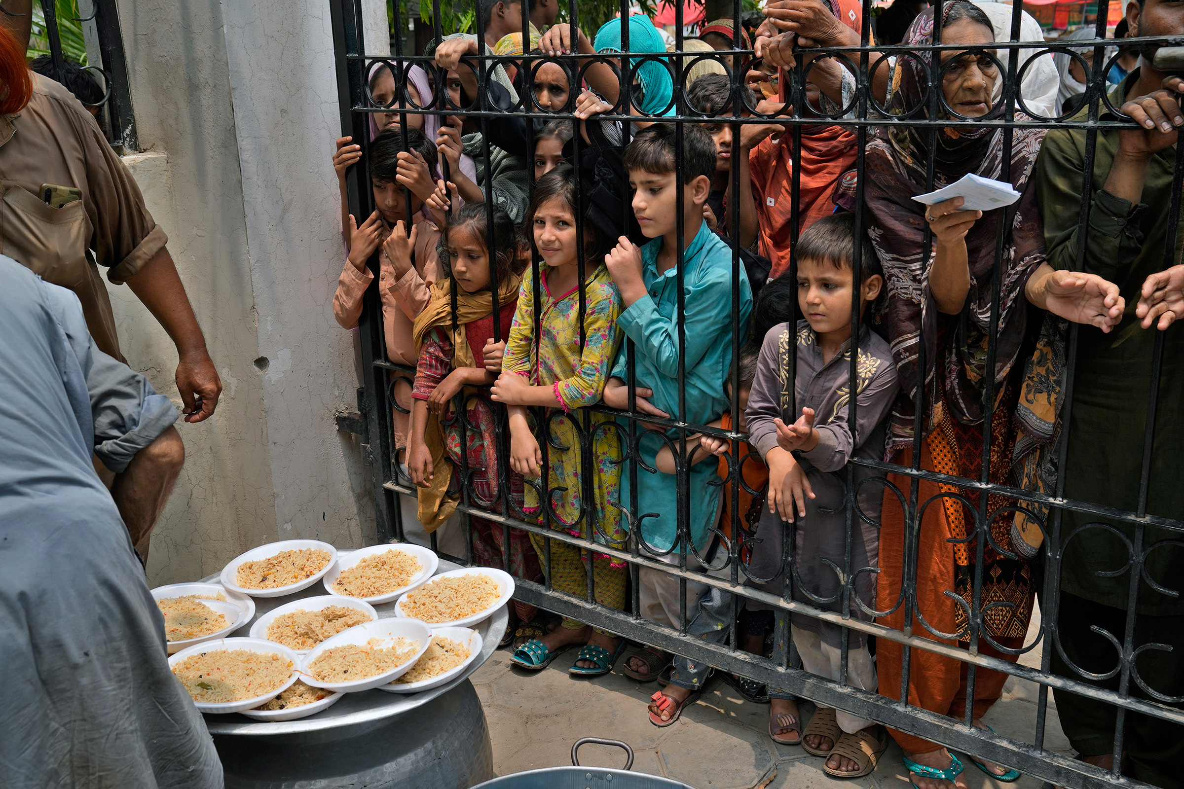 Women and children wait for free food at a distribution point in Lahore, Pakistan, on June. 27.