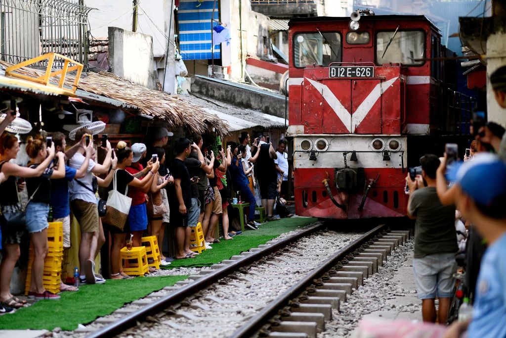Visitors and tourists stand on the sides of a railway track to photograph a passing train in Hanoi, June 9, 2019. (Manan Vatsyayana—AFP via Getty Images)
