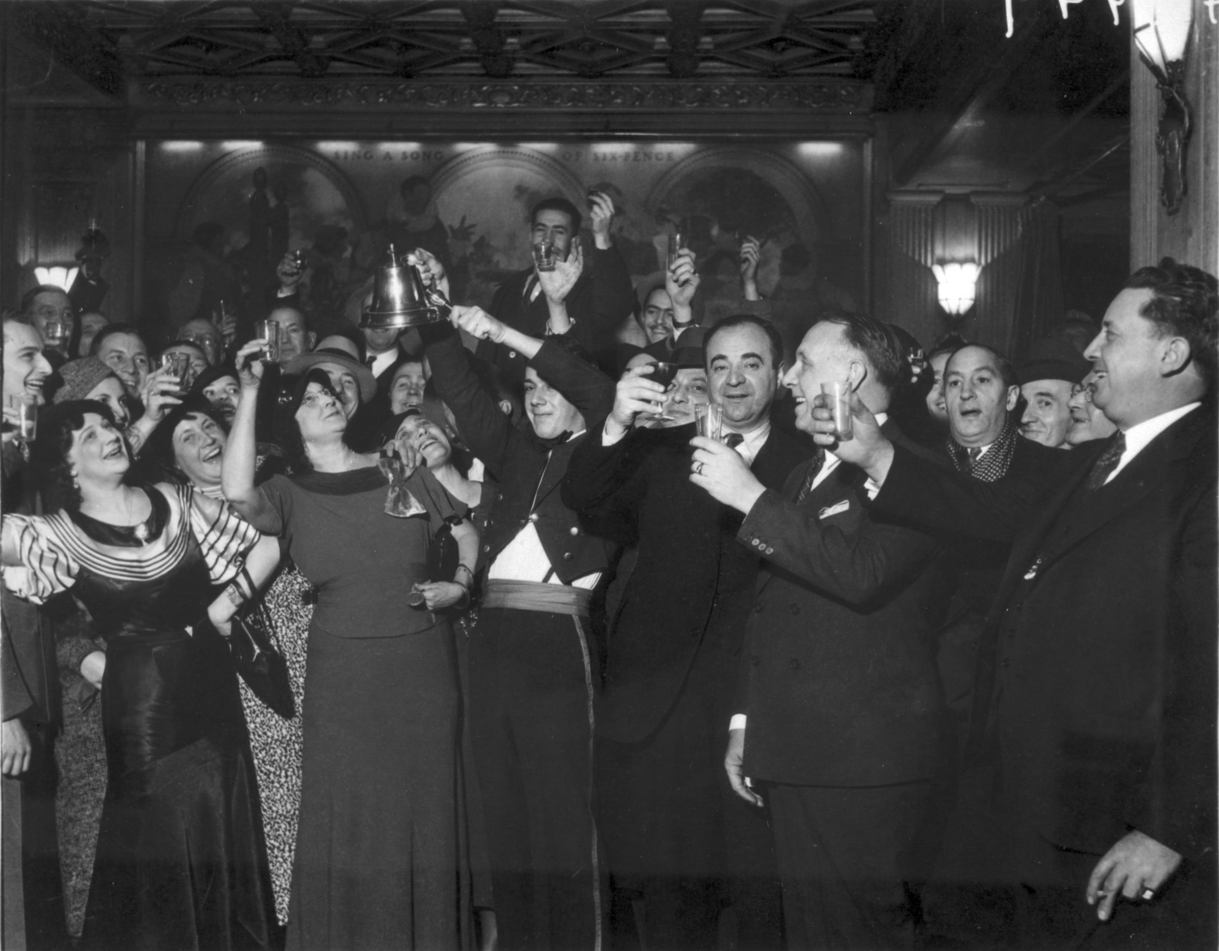 Men and women in a a bar raising glasses celebrating prohibition's end