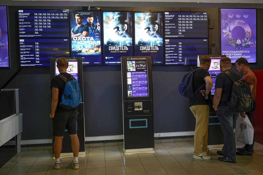 People stand at ticket machines in a cinema lobby in Moscow, Aug. 17, 2023.