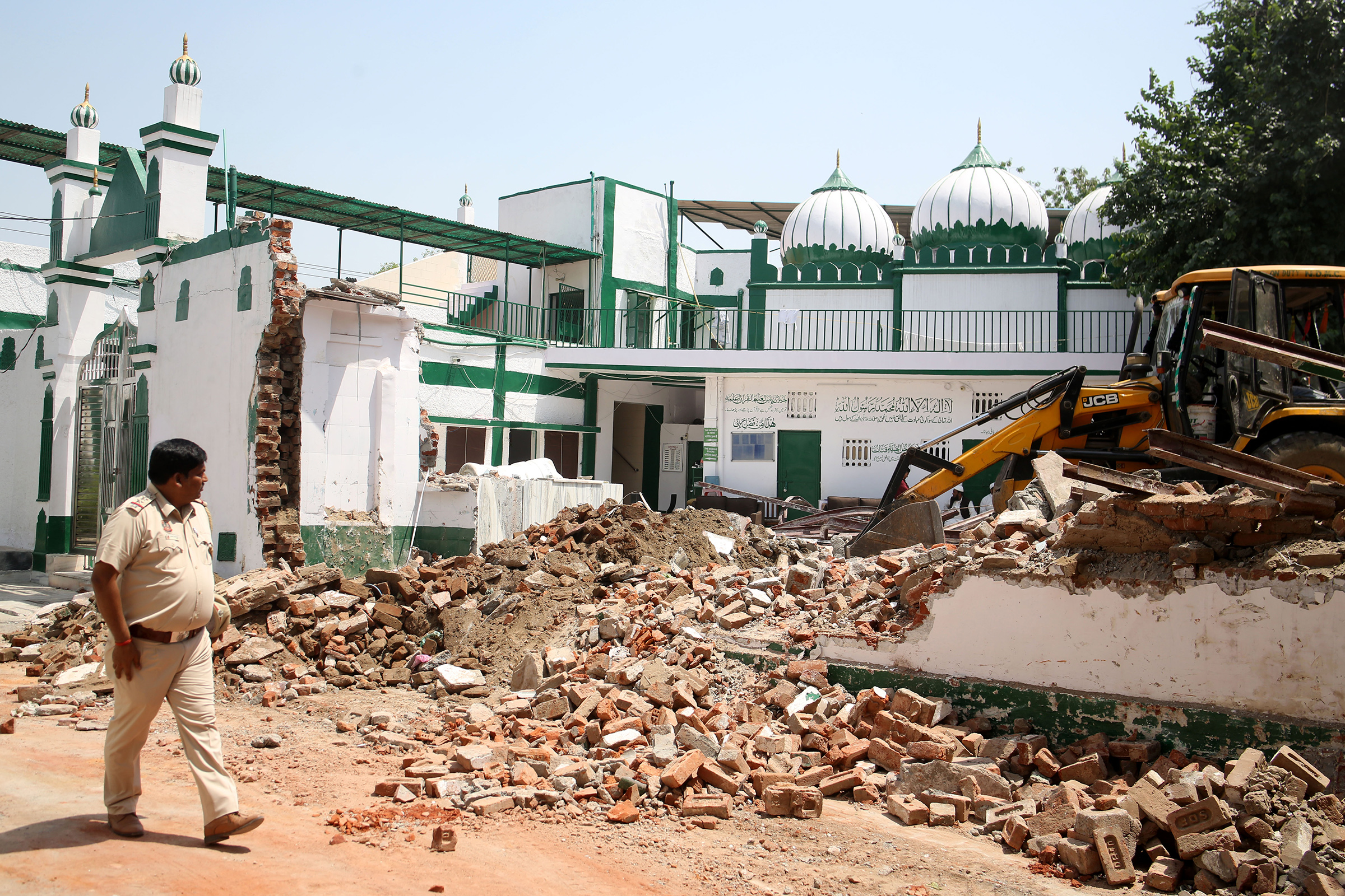 A bulldozer is demolishing an alleged illegal structure of a Bengali market mosque during an anti-encroachment drive by the New Delhi Municipal Corporation (NDMC) on April 11 in New Delhi.