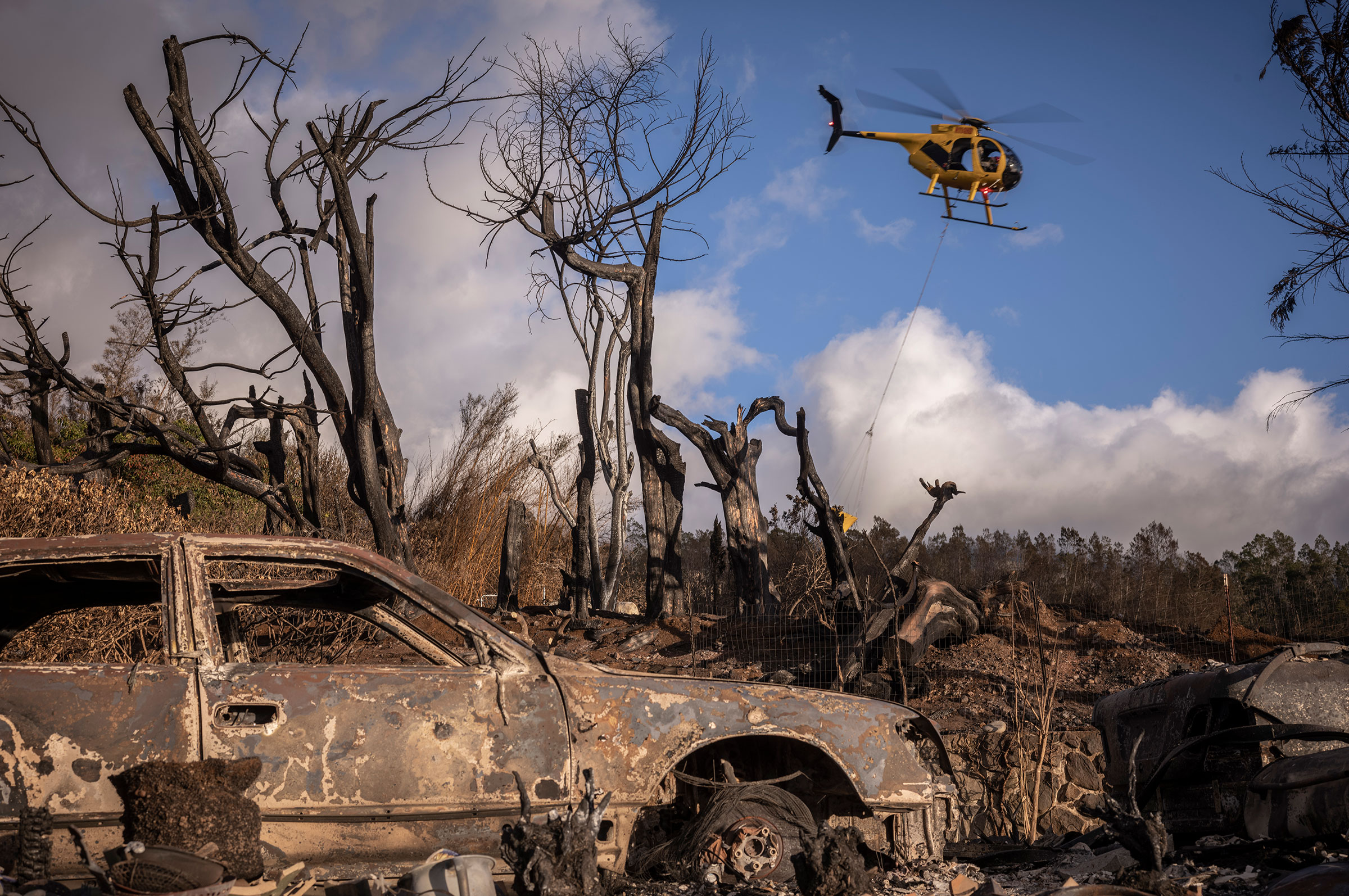 A water-dropping helicopter flies in and out of a neighborhood in Kula after picking up water from a swimming pool of a burned-down house on Aug. 13. (David Butow for TIME)