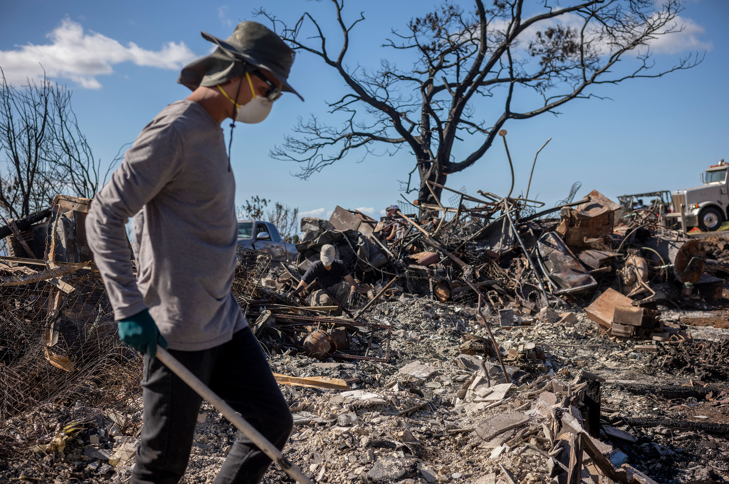 Spencer Kim helps clear debris at the ruins of a house that was burned down