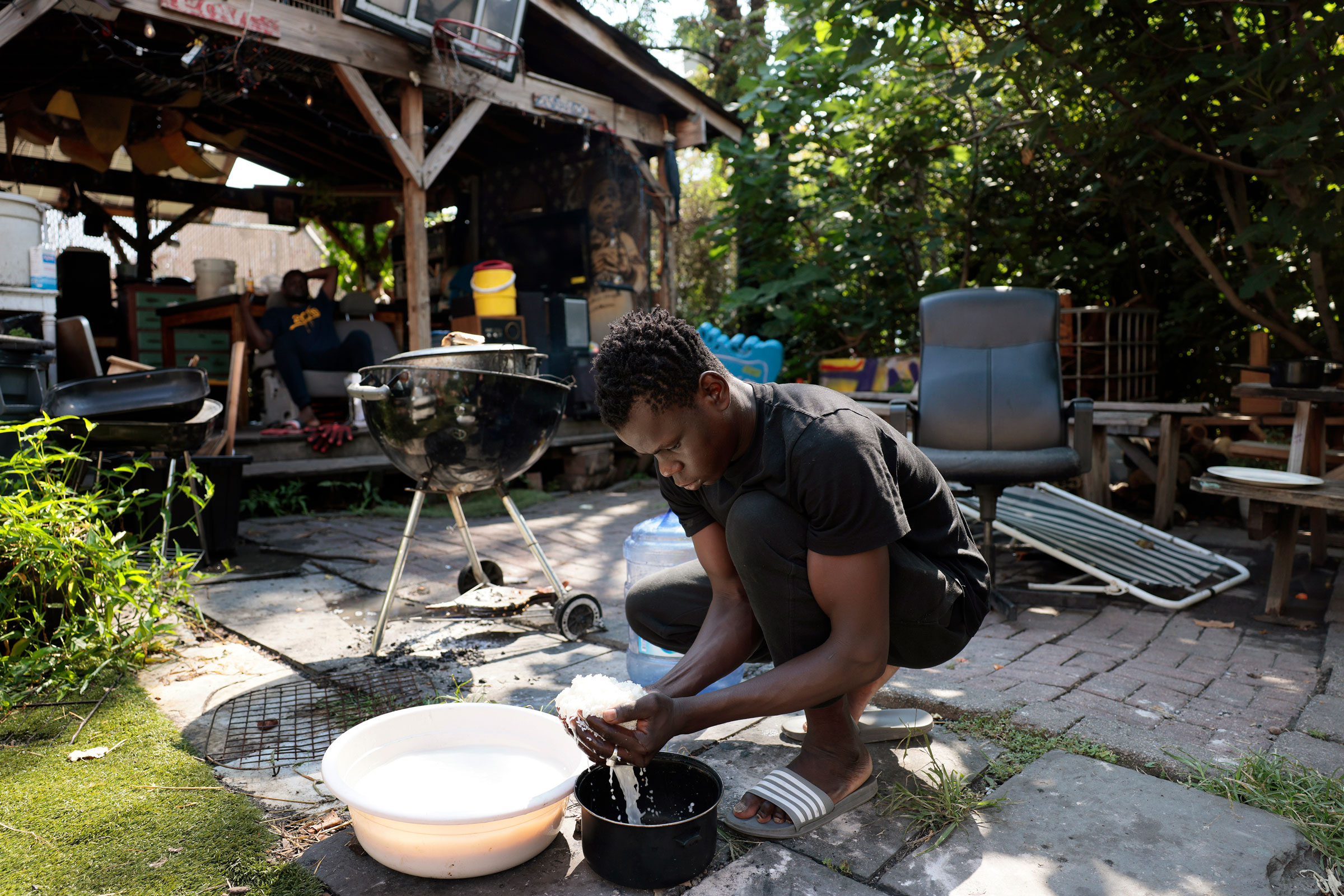 A migrant from Mauritania washes rice at Bushwick City Farm, which had provided migrants who were staying in a shelter across the street with fresh produce and invited them to use their space for cooking, on Aug. 16, 2023. (Jessica Rinaldi—The Boston Globe/Getty Images)