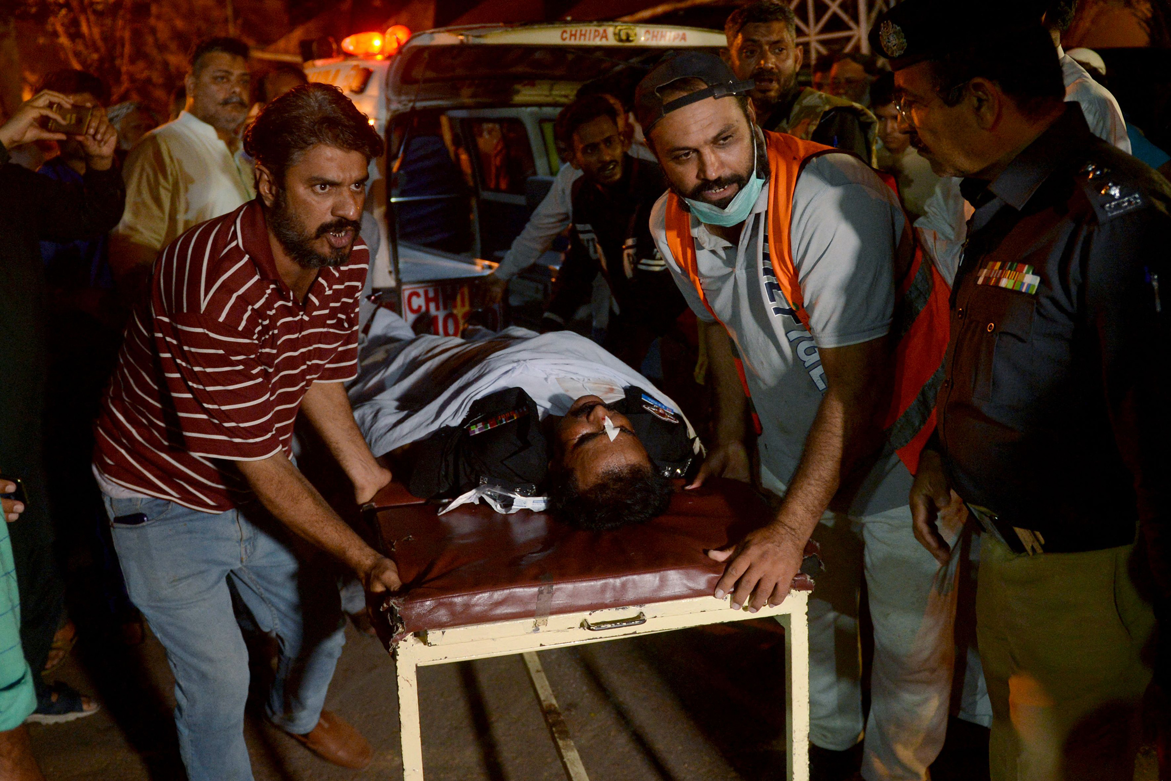 Volunteers carry an injured police officer to a hospital following an attack on a police compound in Karachi on February 17. At least seven people were killed when a Pakistan Taliban suicide squad stormed a police compound in the port city of Karachi, with a gun battle raging for hours.