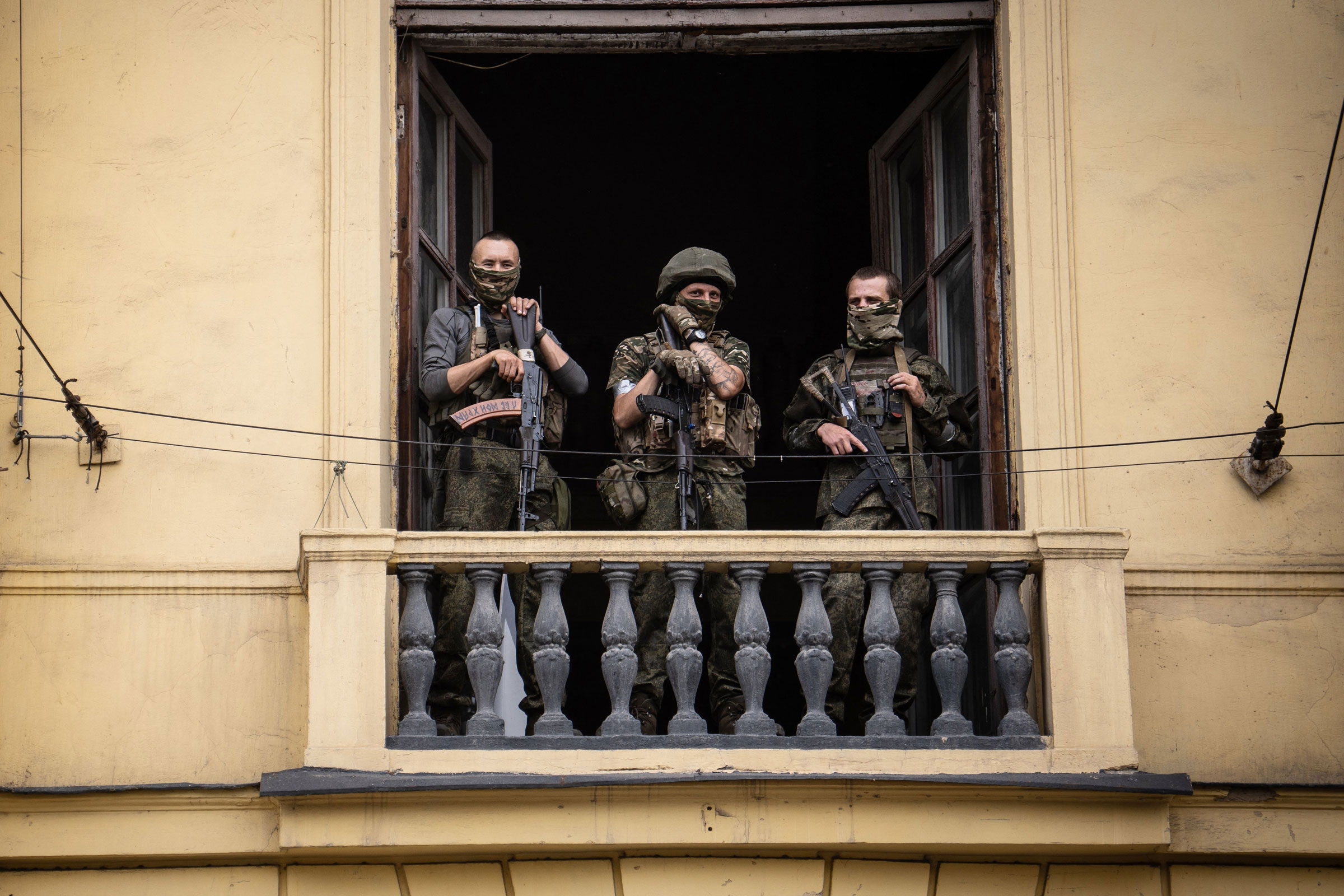 Members of Wagner group carrying weapons stand on a balcony
