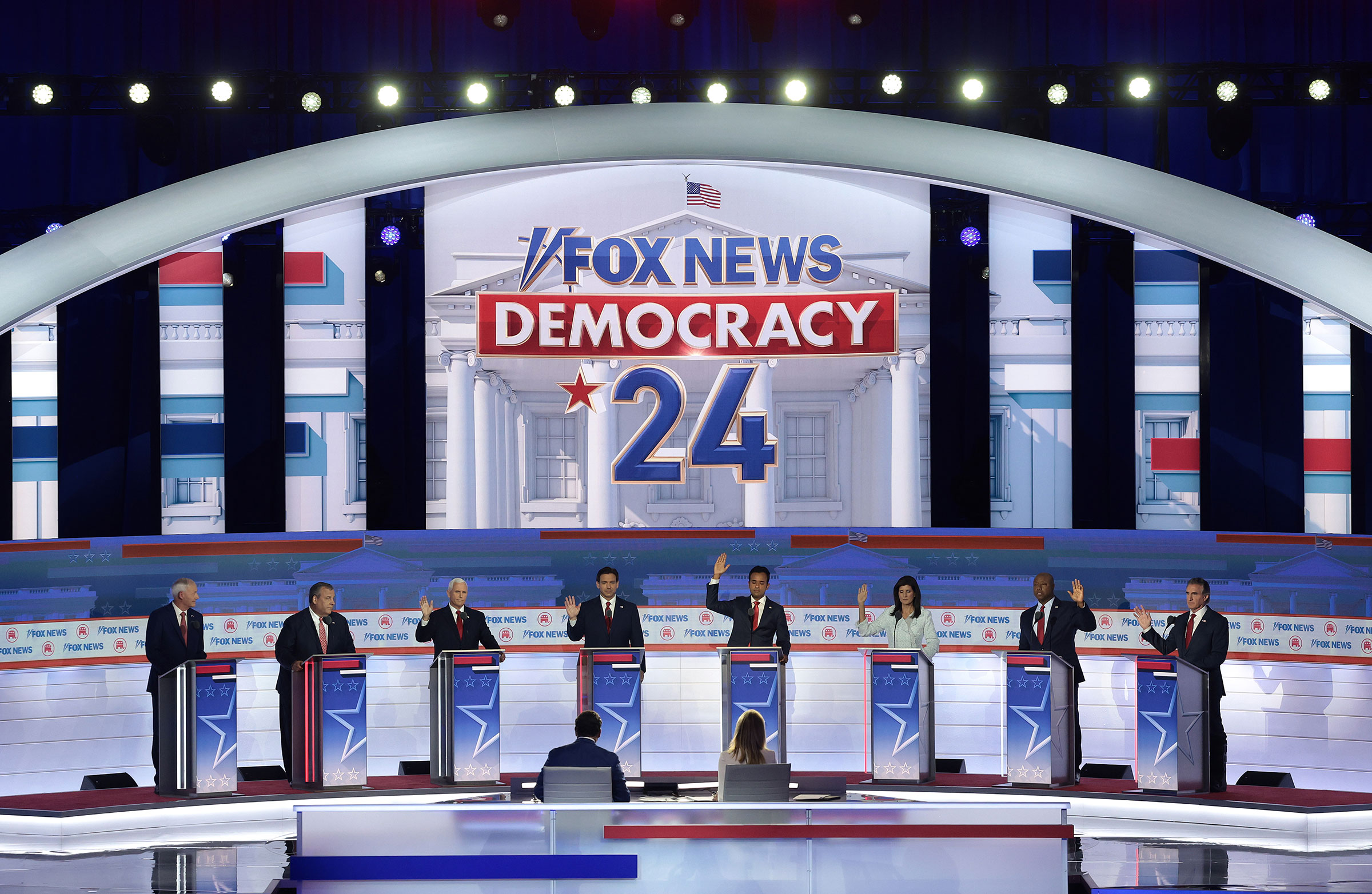 With the exception of Asa Hutchinson and Chris Christie, Republican presidential candidates Mike Pence, Ron DeSantis, Vivek Ramaswamy, Nikki Haley, Tim Scott and Doug Burgum raise their hands to say they would support Donald Trump as the party's presidential nominee. (Win McNamee—Getty Images)