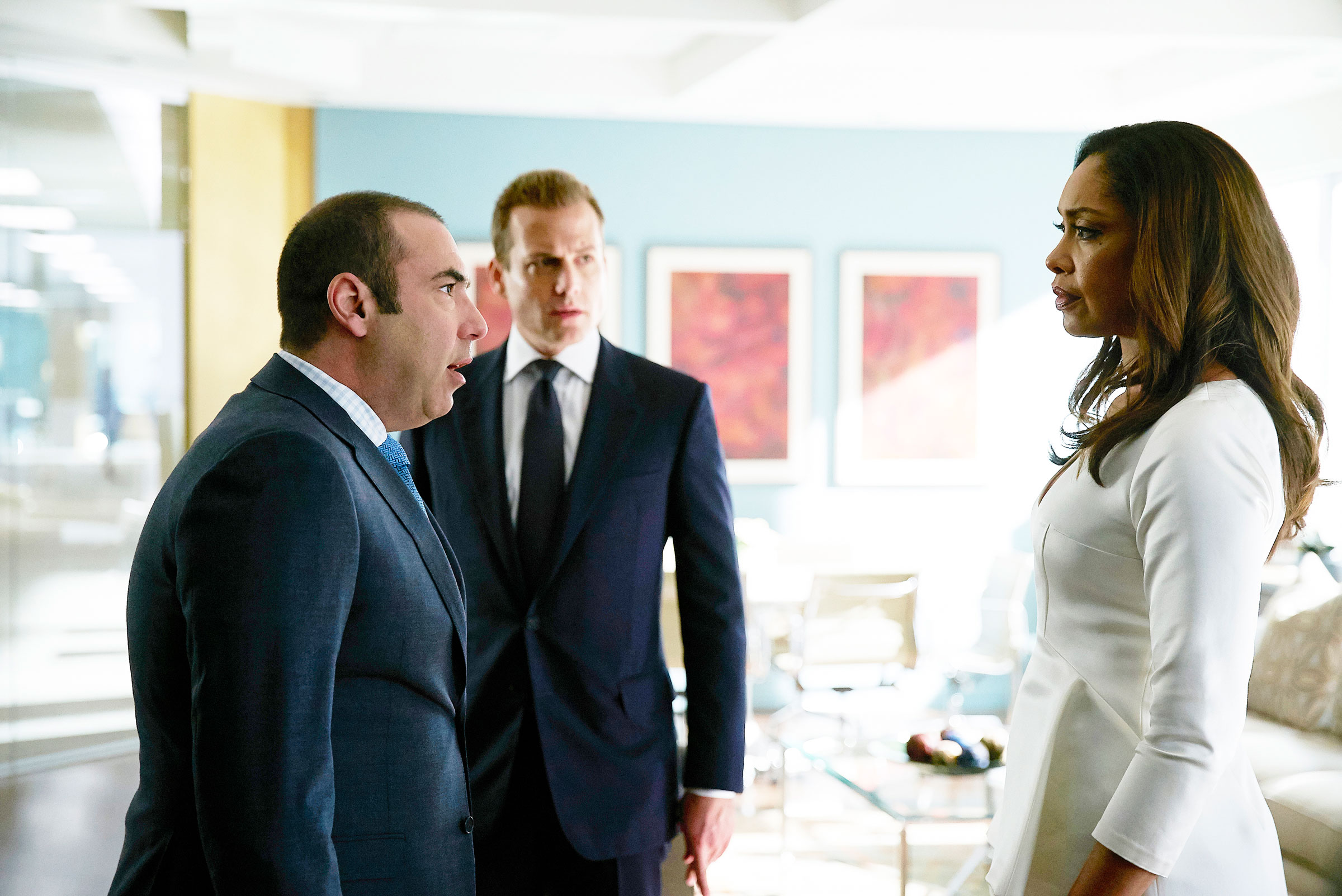still from season 5 of Suits showing Rick Hoffman as Louis Litt, Gabriel Macht as Harvey Specter, and Gina Torres as Jessica Pearson