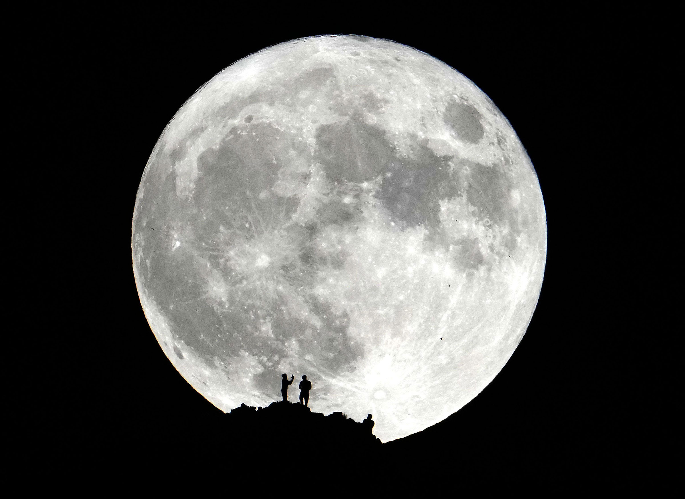 Hikers watch the super blue moon from the summit of Piestewa Peak in Phoenix on Aug. 30, 2023. (Rob Schumacher—The Republic/USA TODAY NETWORK/Reuters)