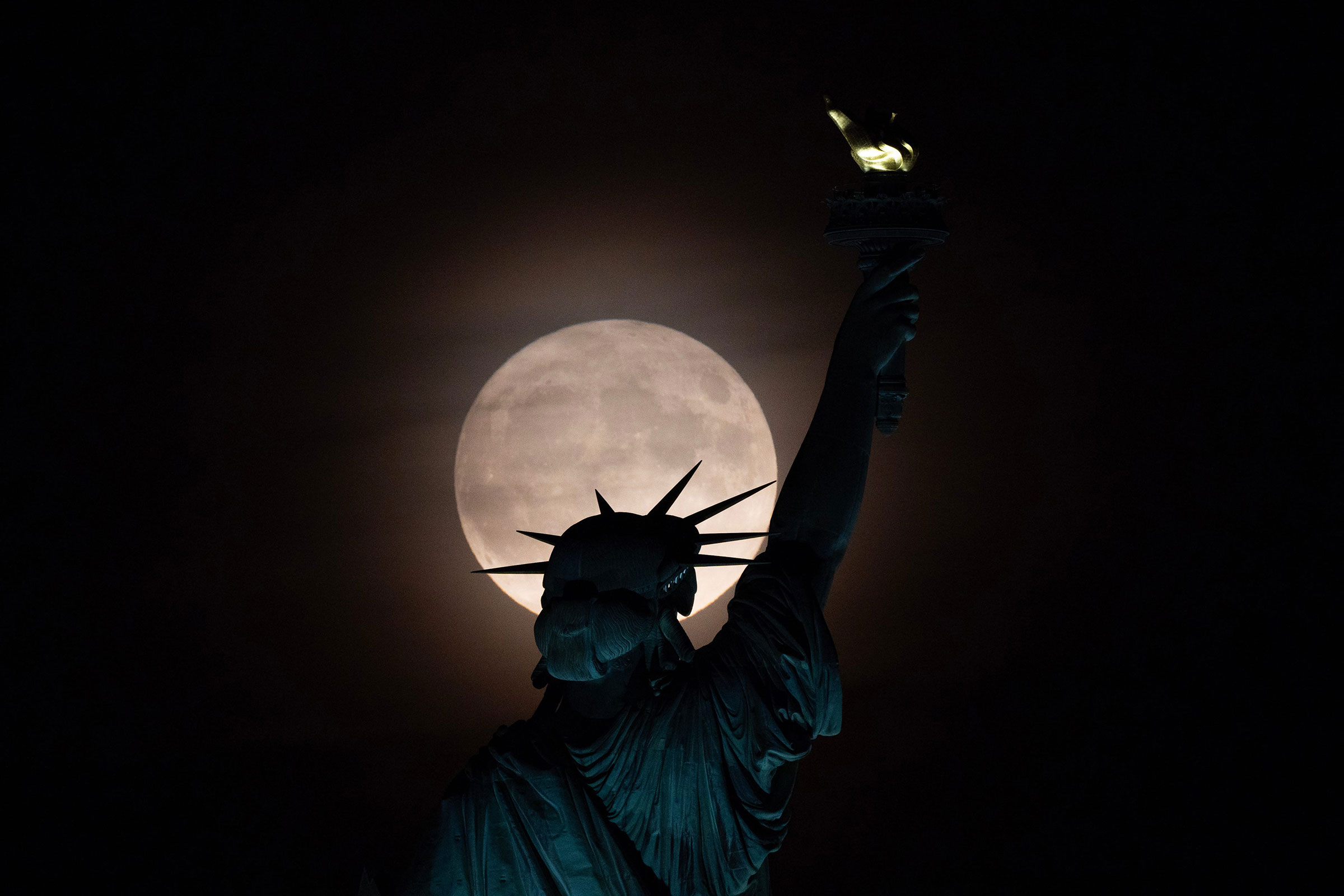 The Super Blue Moon rises behind the Statue of Liberty seen from Liberty State Park in Jersey City, NJ on Aug. 30, 2023.