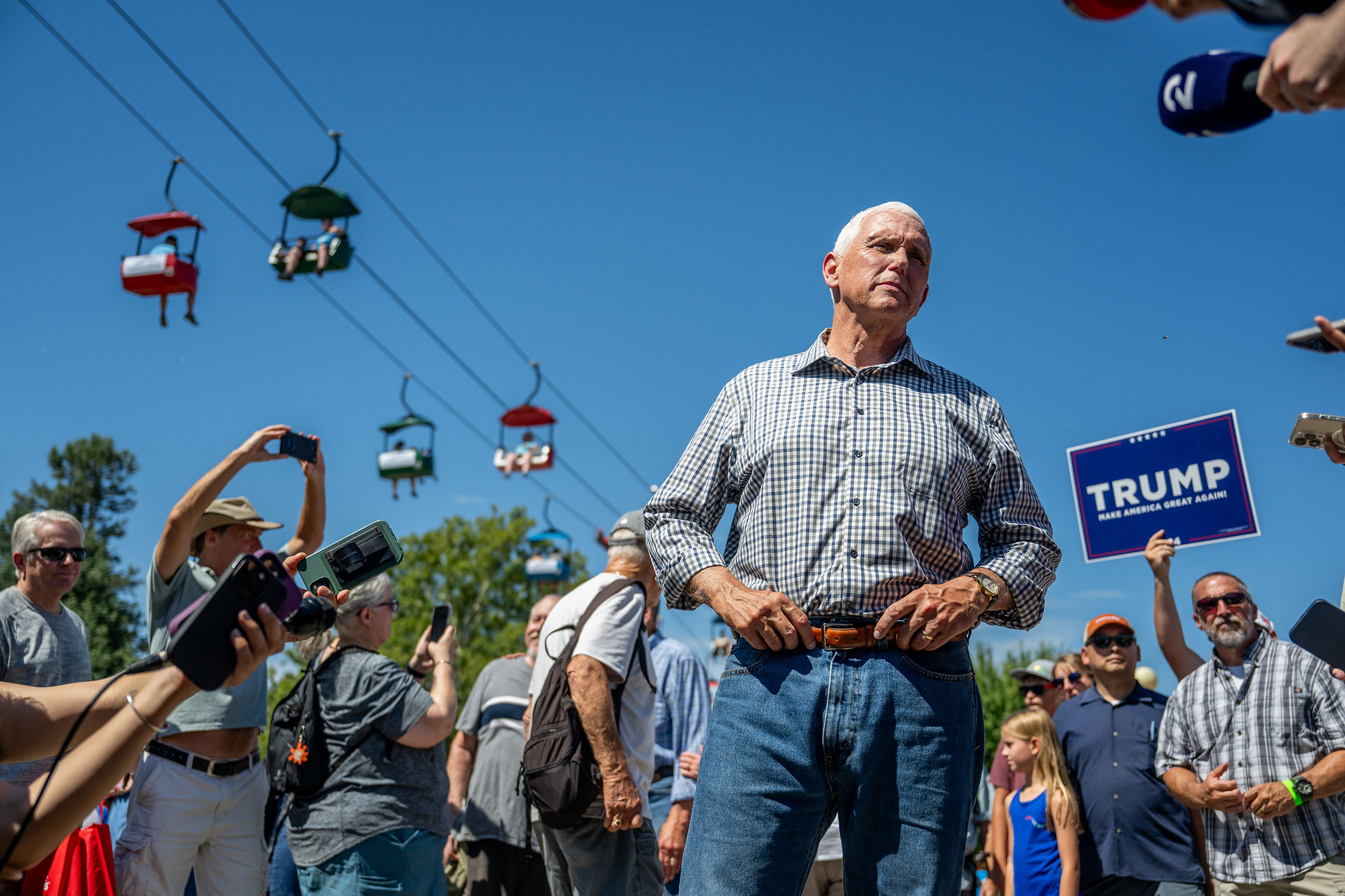 Mike Pence stands with his hands on his belt and looks off at reporters who are surrounding him at the Iowa State Fair