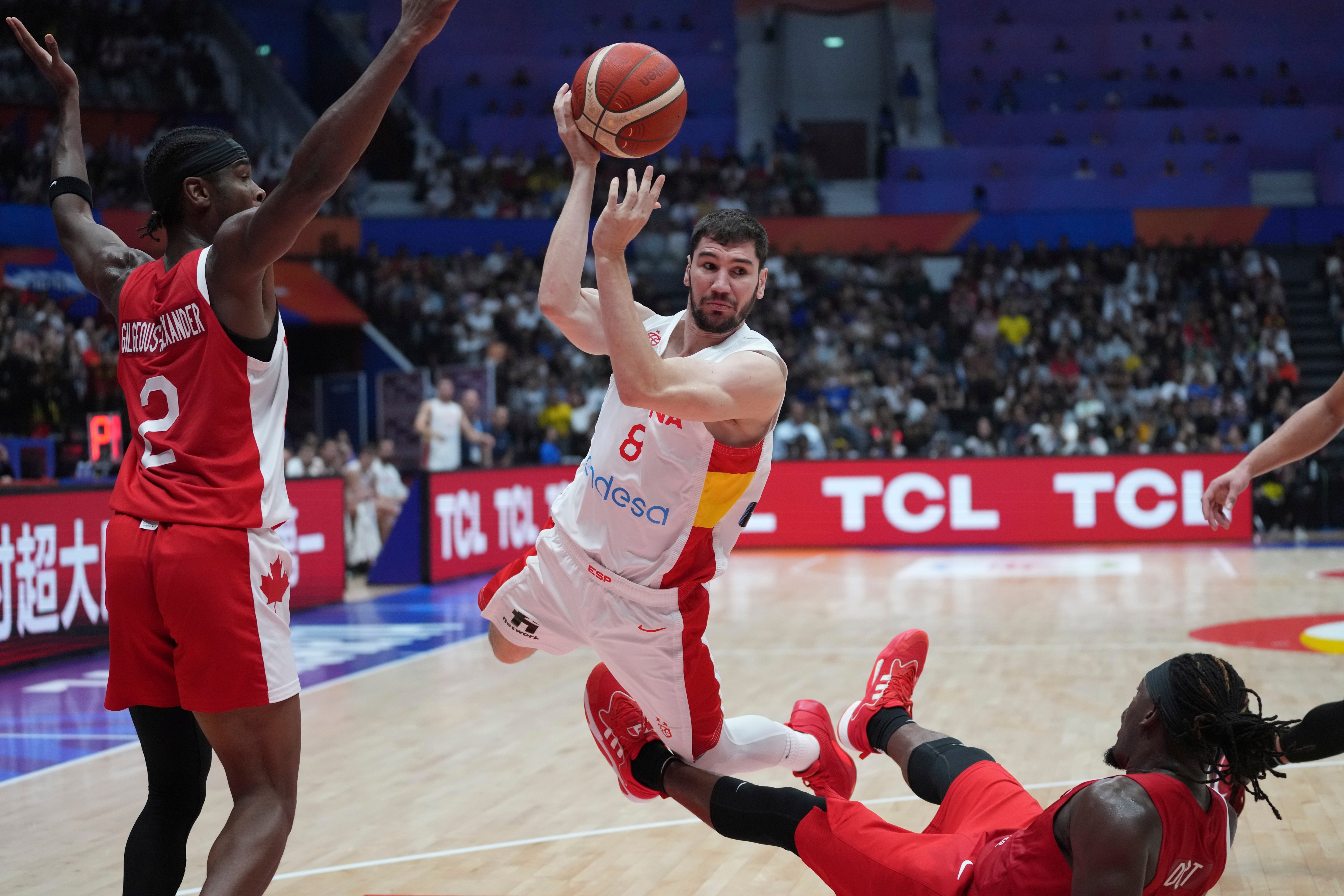 Spain guard Dario Brizuela (8) leaps as he drives against Canada guards Shai Gilgeous-Alexander (2) and Luguentz Dort (0) during the Basketball World Cup second round match between Spain and Canada at the Indonesia Arena stadium in Jakarta, Indonesia, on Sept. 3, 2023.  (Tatan Syuflana—AP)
