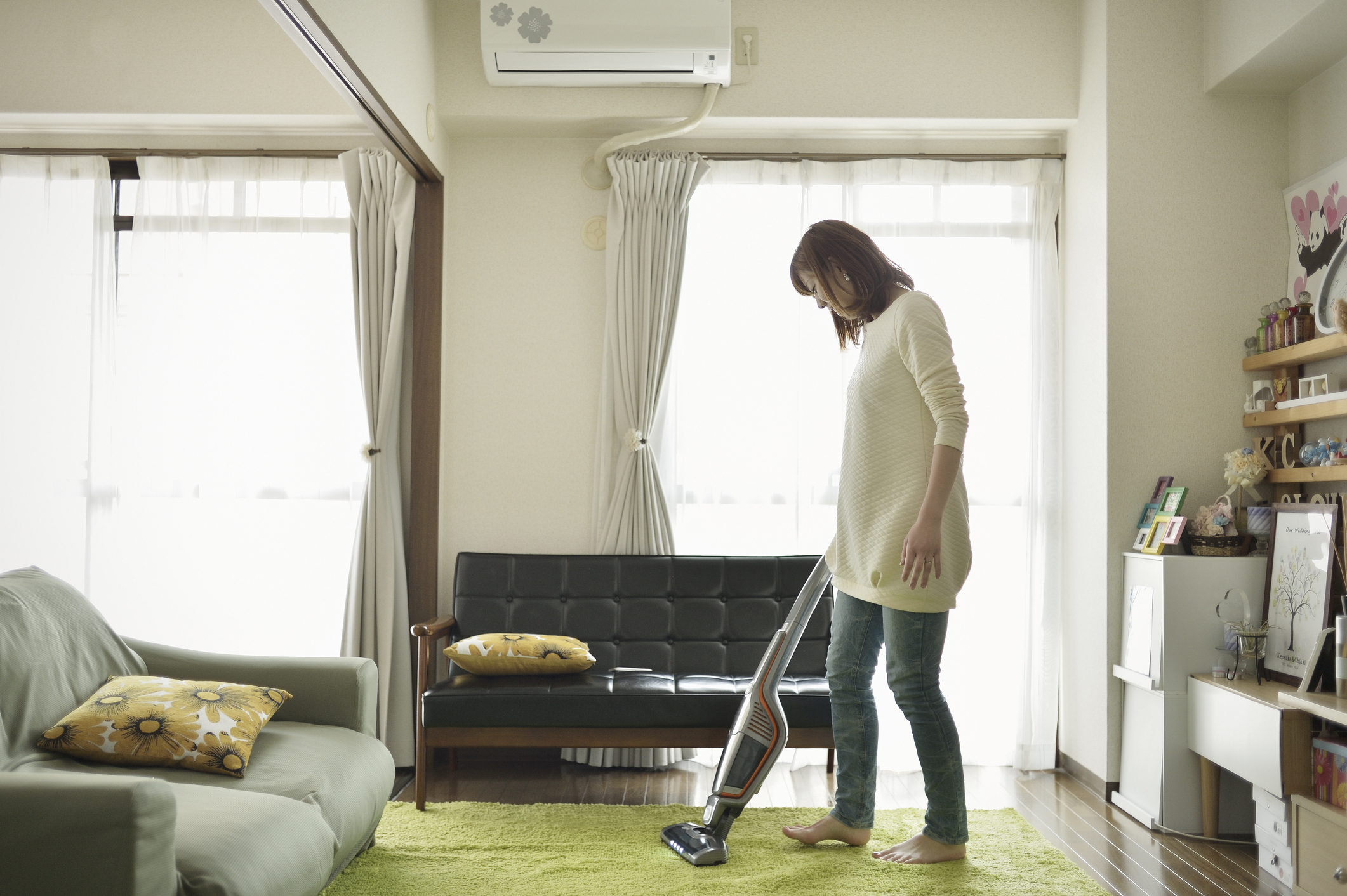 A woman cleans the room with a vacuum cleaner