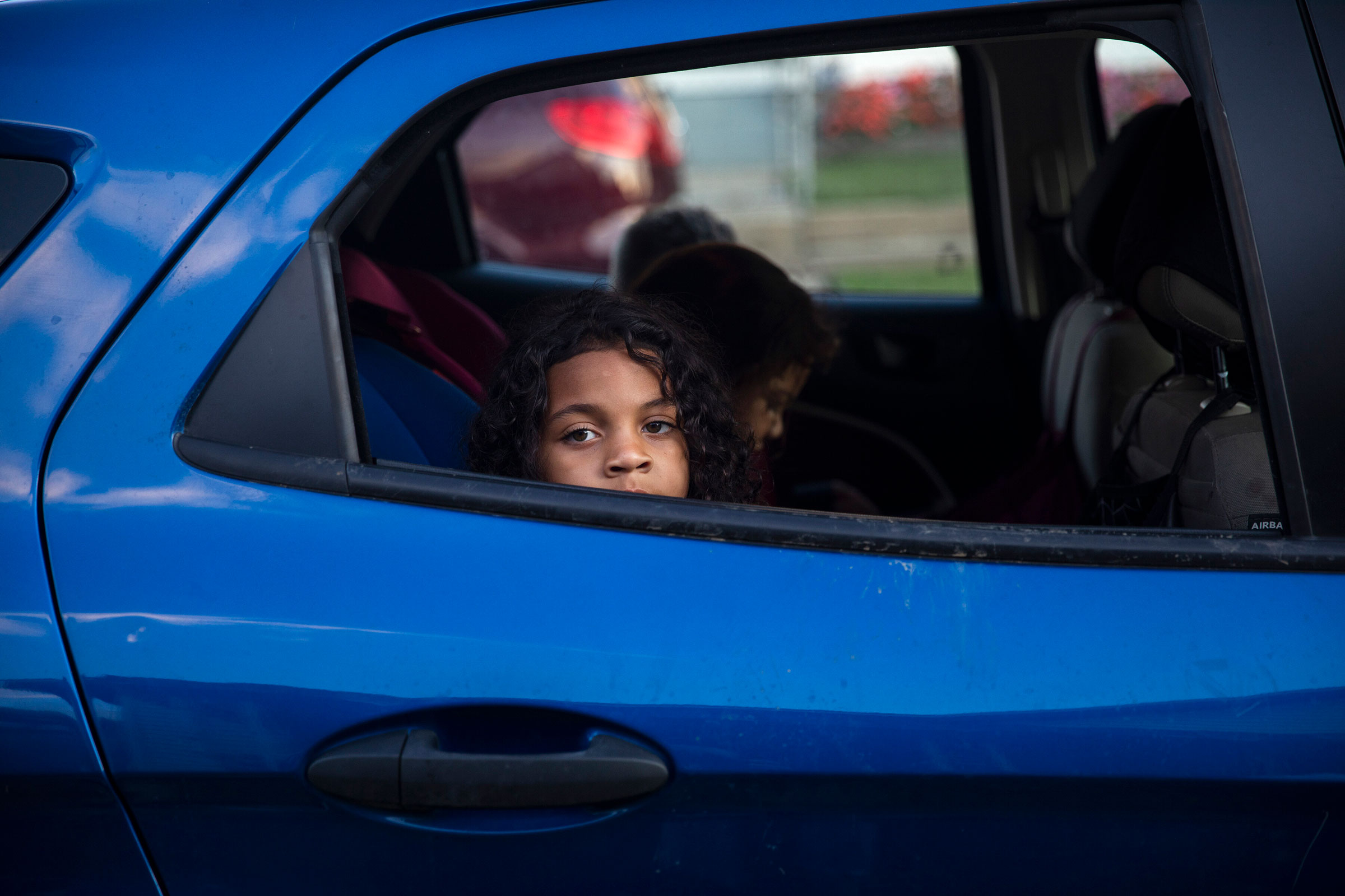 a young boy looks out the window of a blue car