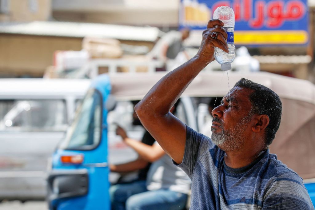 An Iraqi man splashes water on his face to cool down during a heatwave in the Shorja market in central Baghdad on Aug. 13, 2023.