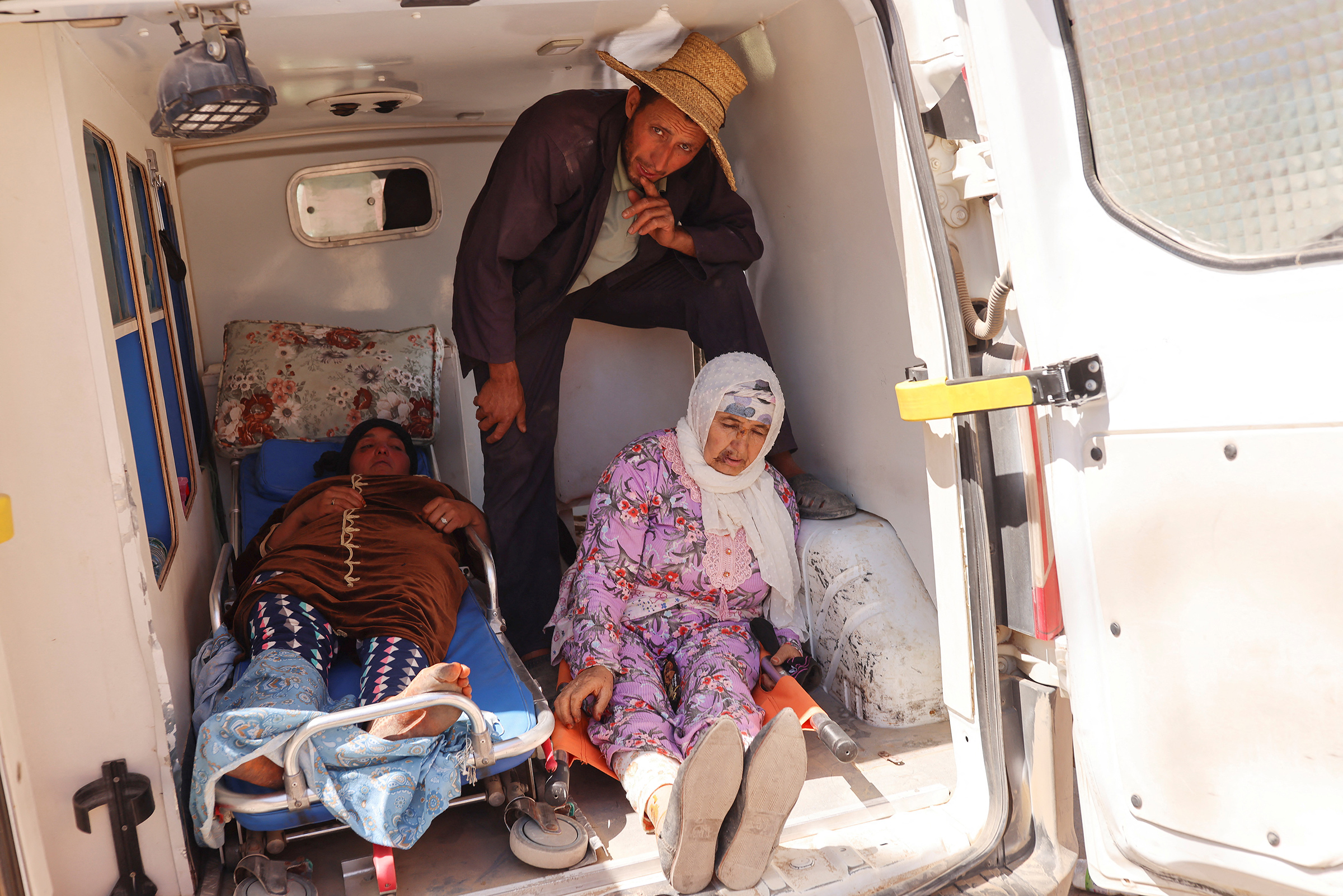 A man looks on, next to women who were rescued, in the back of an ambulance, in the aftermath of a deadly earthquake, in Amizmiz, Morocco, Sept. 10. (Nacho Doce—Reuters)
