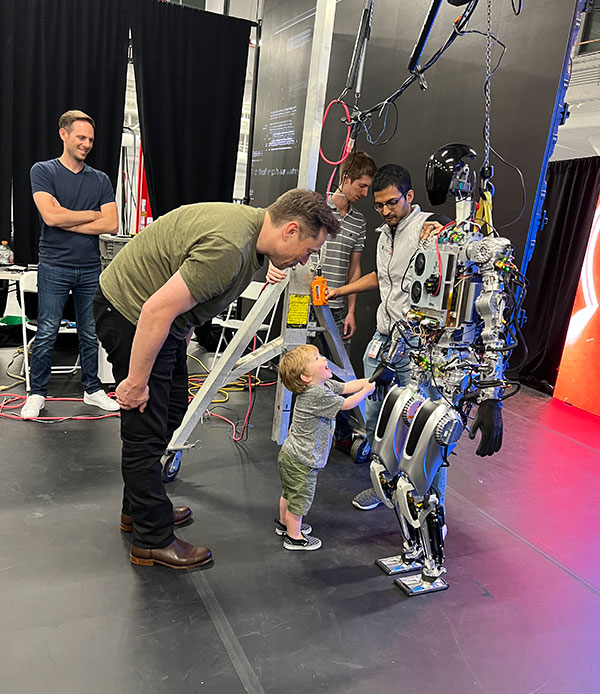 Musk and his son X looking at Optimus the humanoid robot