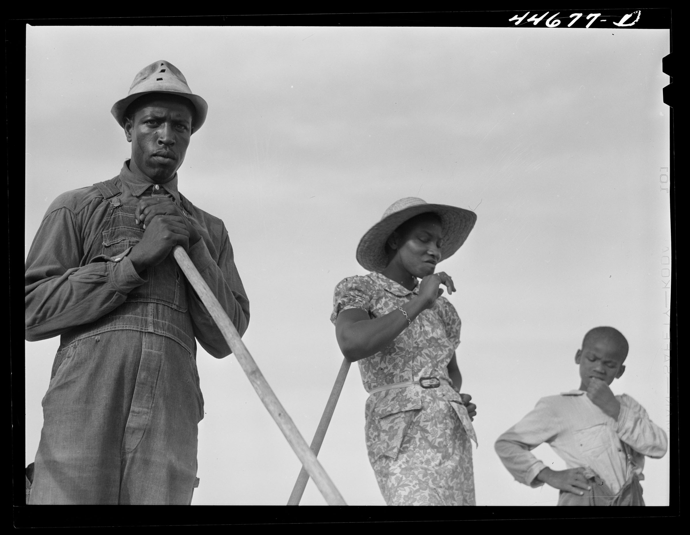 Black farmers standing and a cloudy sky in the background.