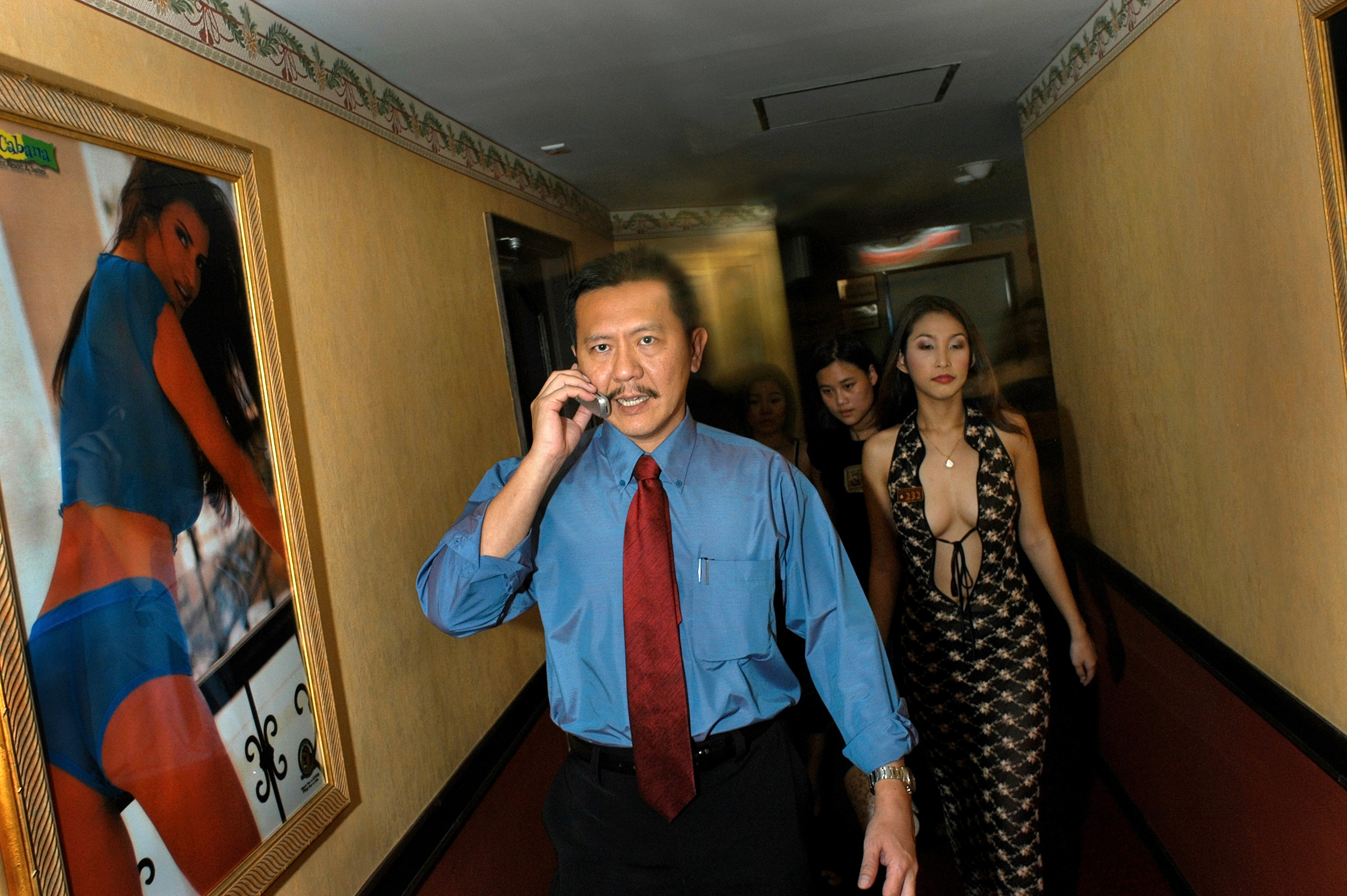 Chuwit Kamolvisit, then 42, talks on his mobile phone as he walks down the corridor of the Copacabana, one of his Bangkok establishments, on Oct. 2, 2003.