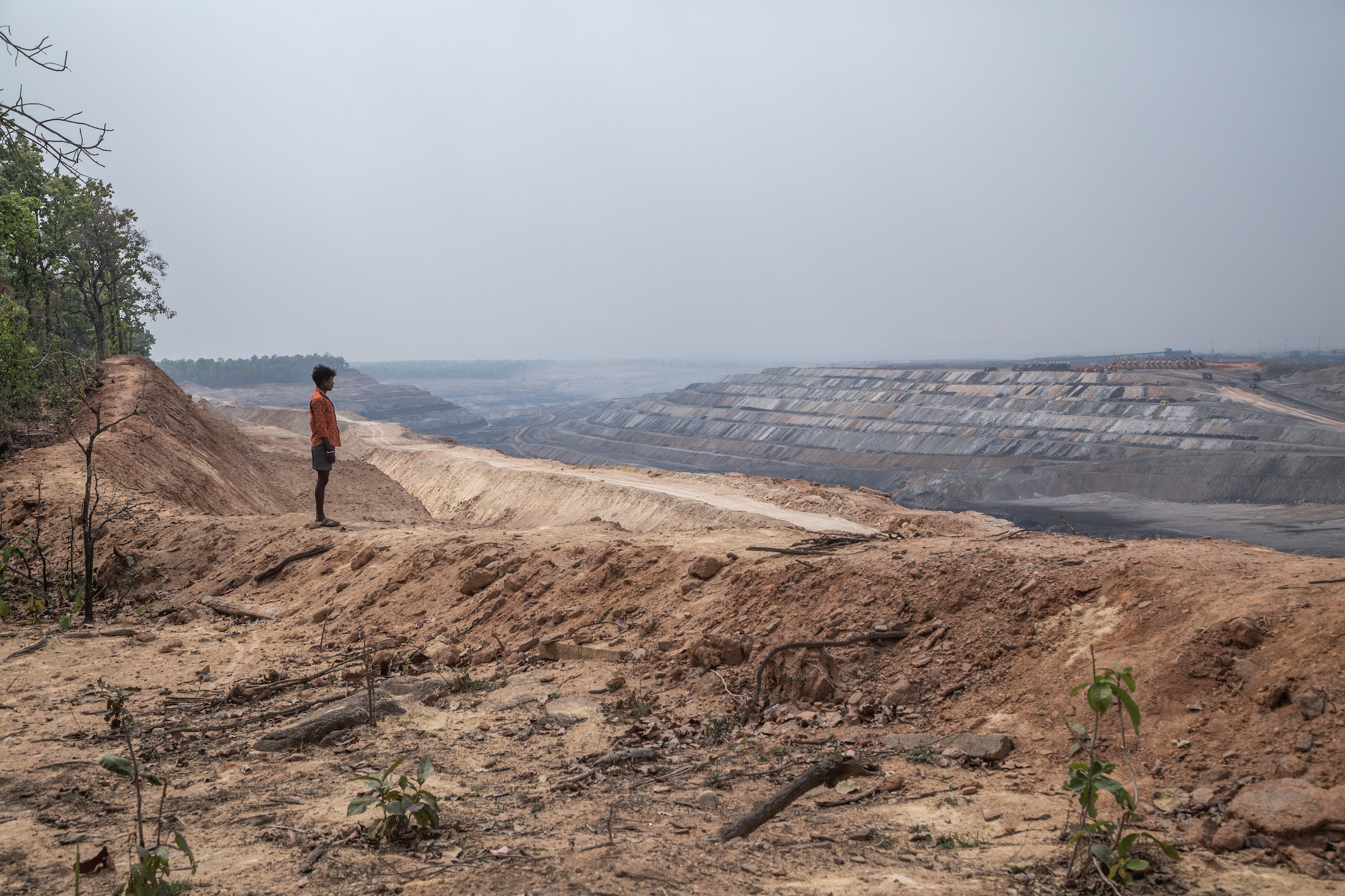 A tribal villager is standing in front of PEKB coal mine in Chhattisgarh district.