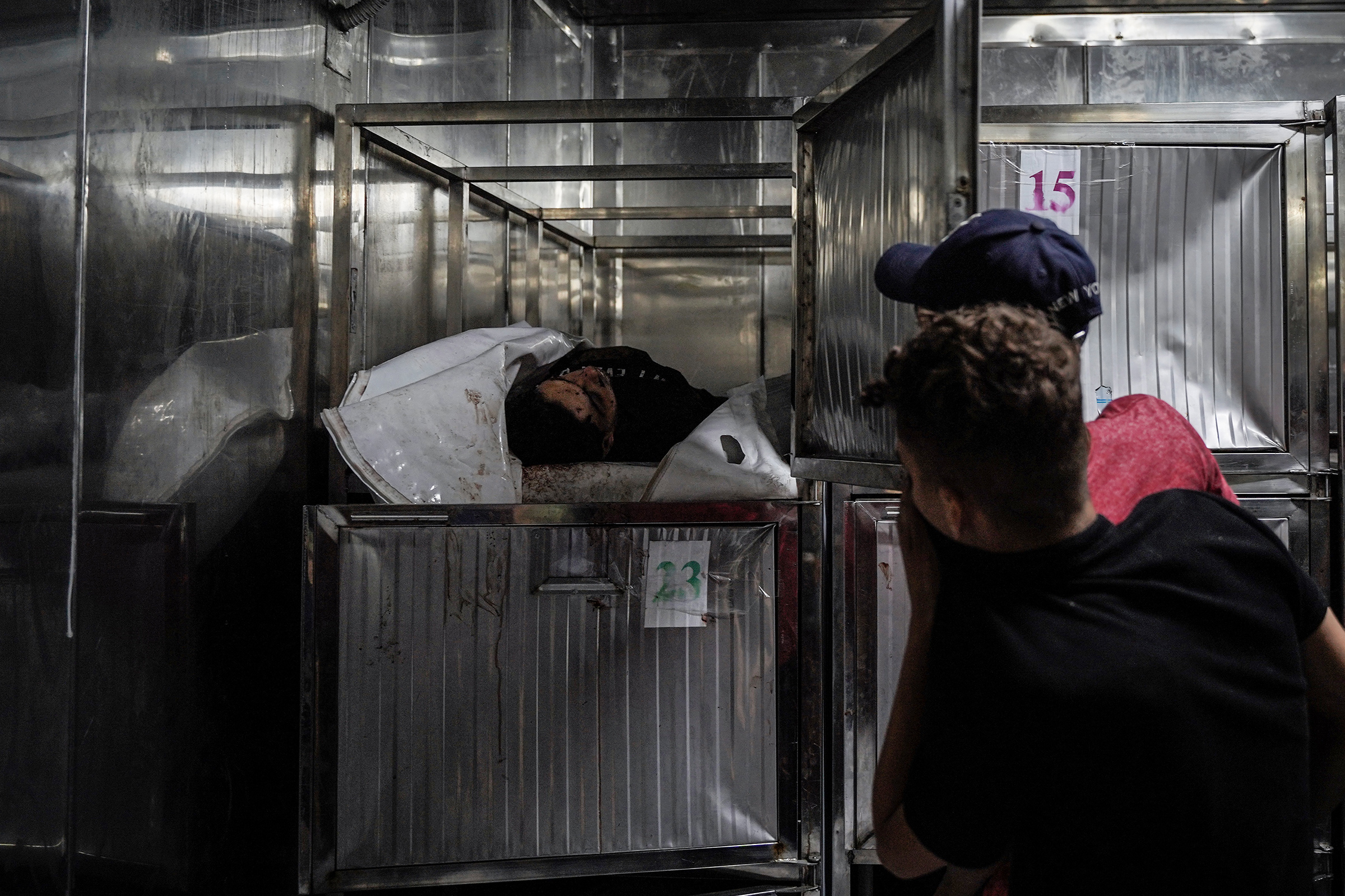 Two Palestinian teenagers look sadly at their relative while he is inside mortuary refrigerators, Oct. 9.