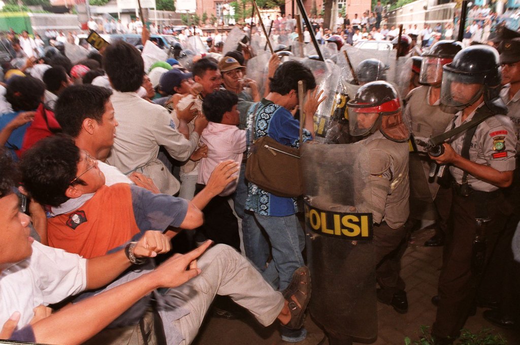 An Indonesian student kicks at riot policemen as an anti-government demonstration turns violent at the gate of Sahid University in Jakarta on April 29, 1998. Clashes erupted as some 300 students demanding then President Suharto step down for his handling of the country's economic crisis were prevented from marching outside their campus.