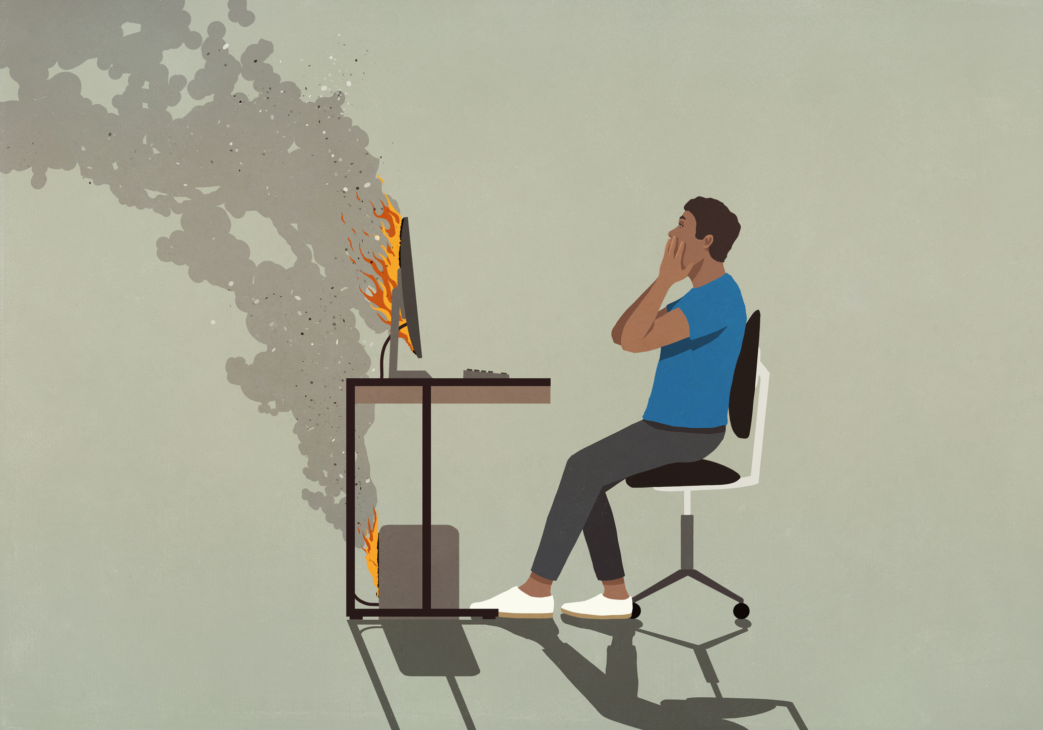 Shocked man sitting at smoking computer on fire
