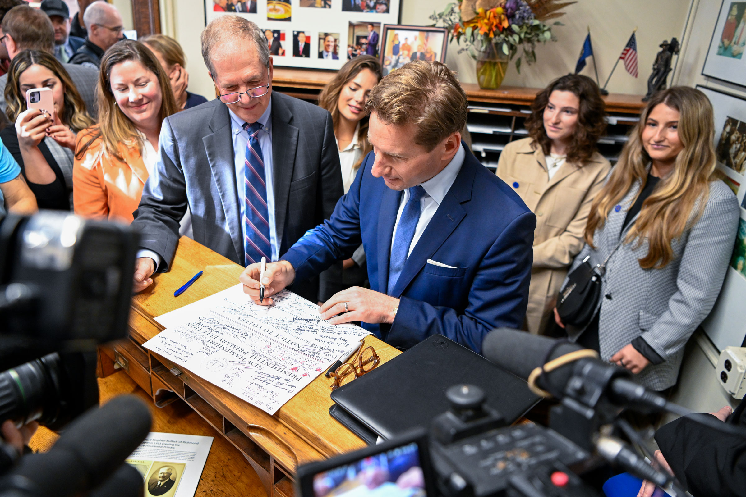 Dean Phillips signs a flyer after handing over his declaration of candidacy form in New Hampshire