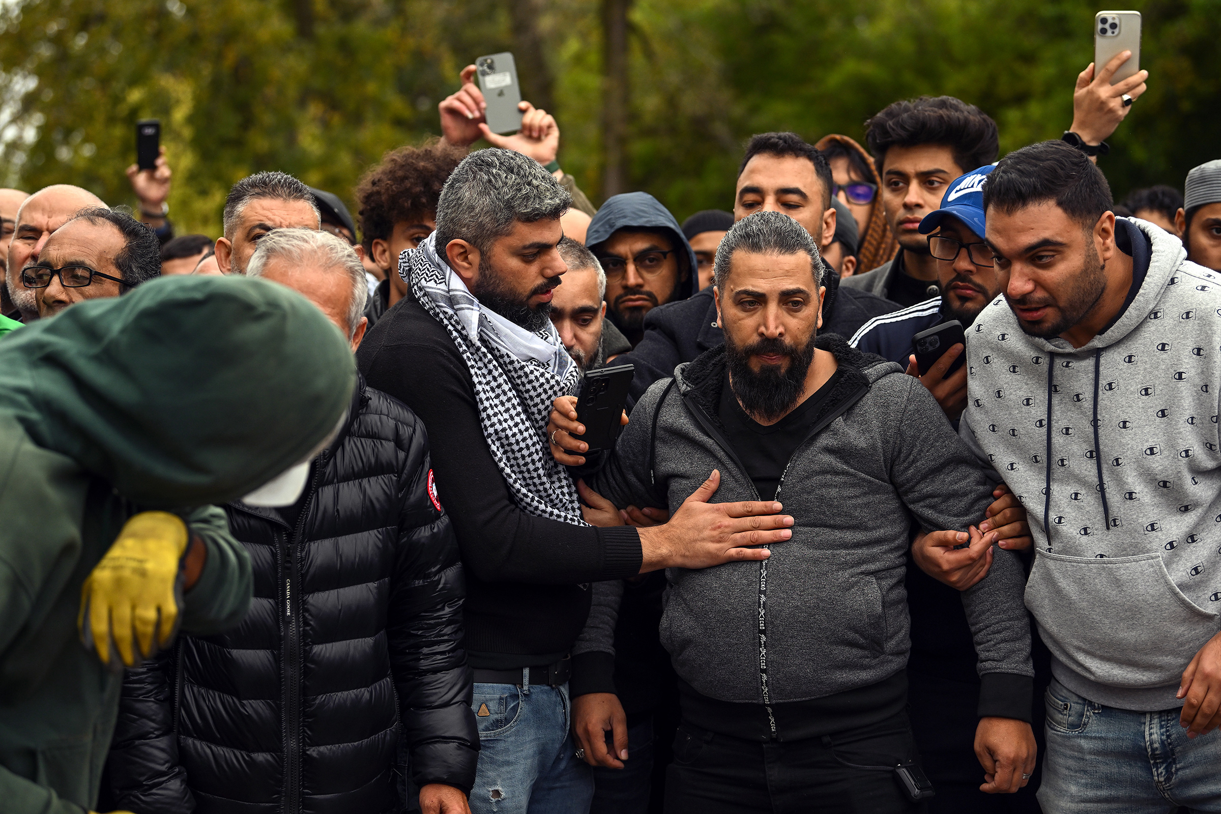 Oday Al-Fayoumi, center in gray hoodie, watches as his 6-year-old Palestinian American Wadea Al-Fayoumi is buried at Parkholm Cemetery on Oct. 16 in LaGrange, Ill.