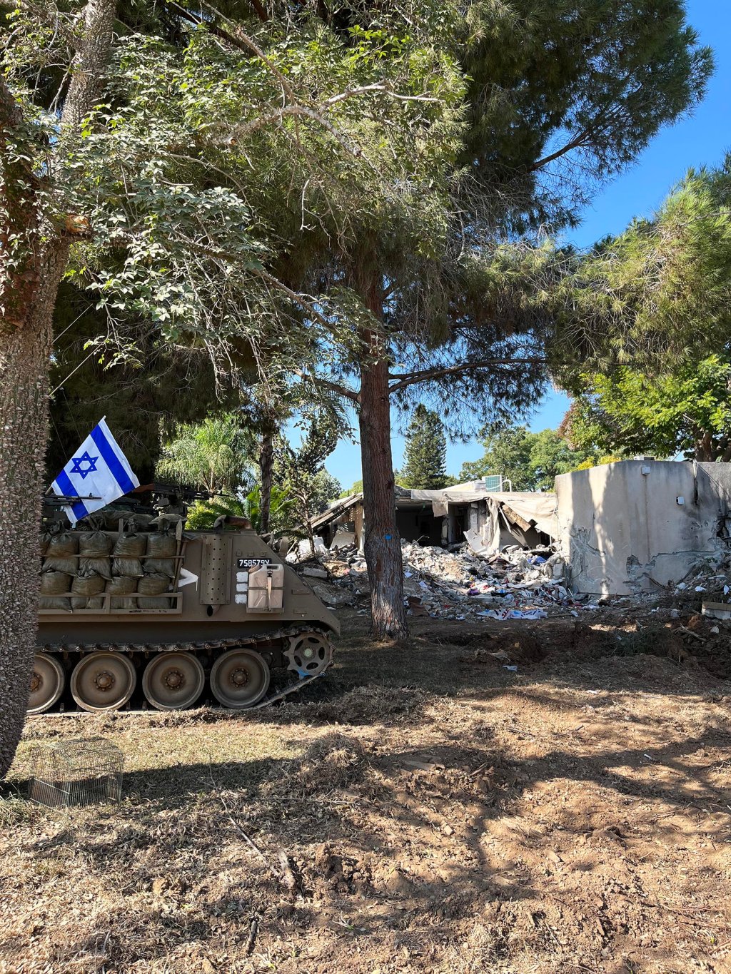 An Israeli Defense Force tank parks next to a destroyed home in Kfar Aza.