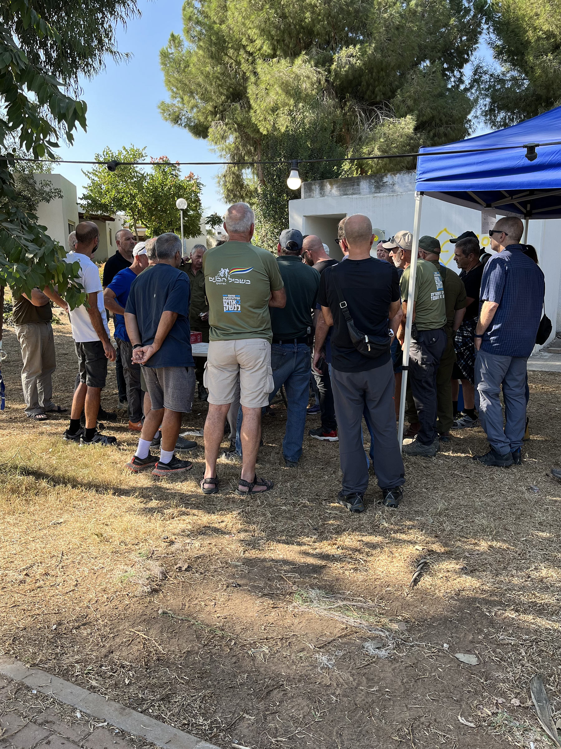 A group of volunteers await clean up orders in Kfar Aza. Residents from Kfar Aza and other nearby kibbutzim meet as frequently as they are allowed to rebuild the kibbutz.