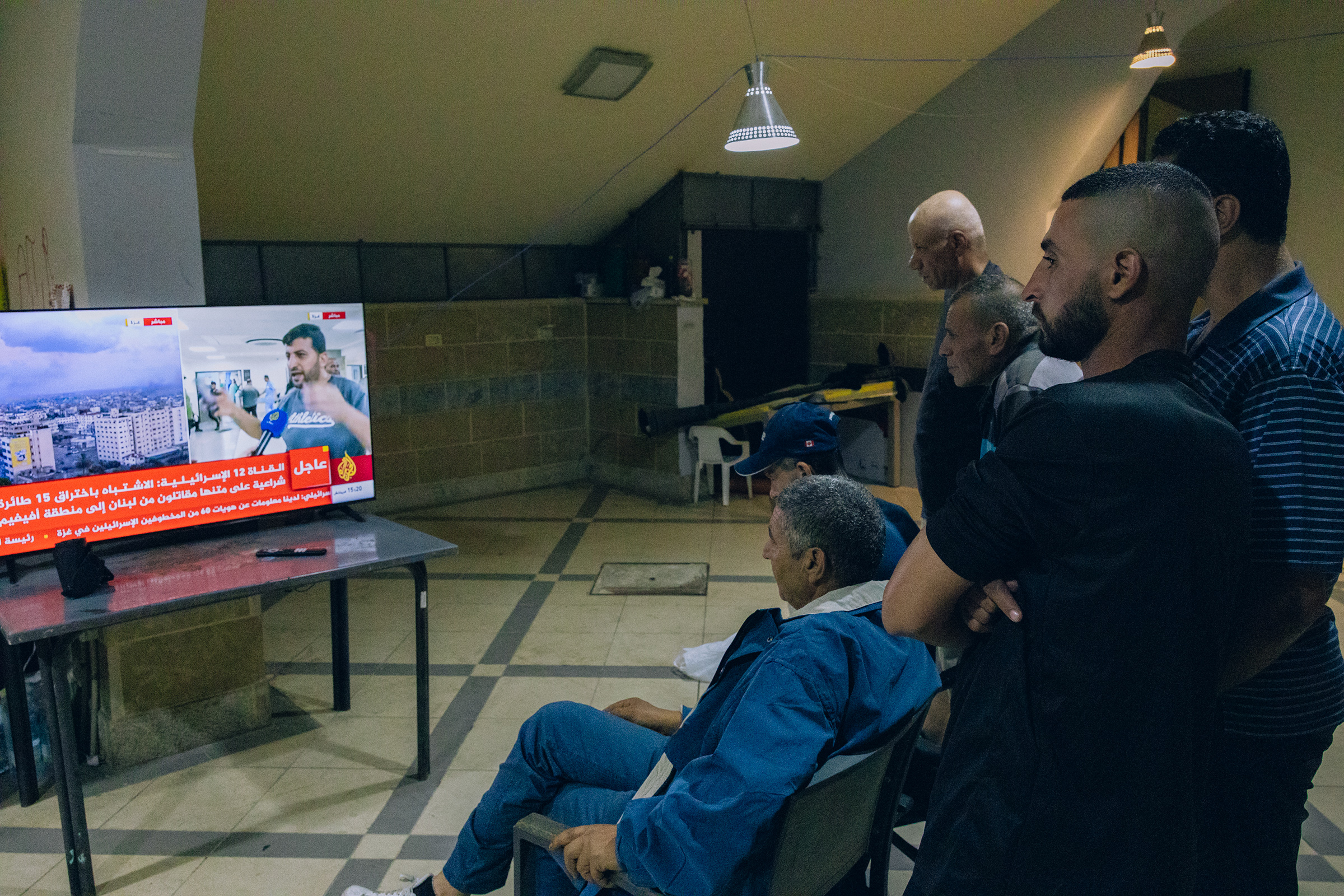 A group of Palestinian workers from Gaza at the Sarriyeh sports club in the West Bank city of Ramallah watch an Al Jazeera news broadcast from a hospital in Gaza, Oct. 12.