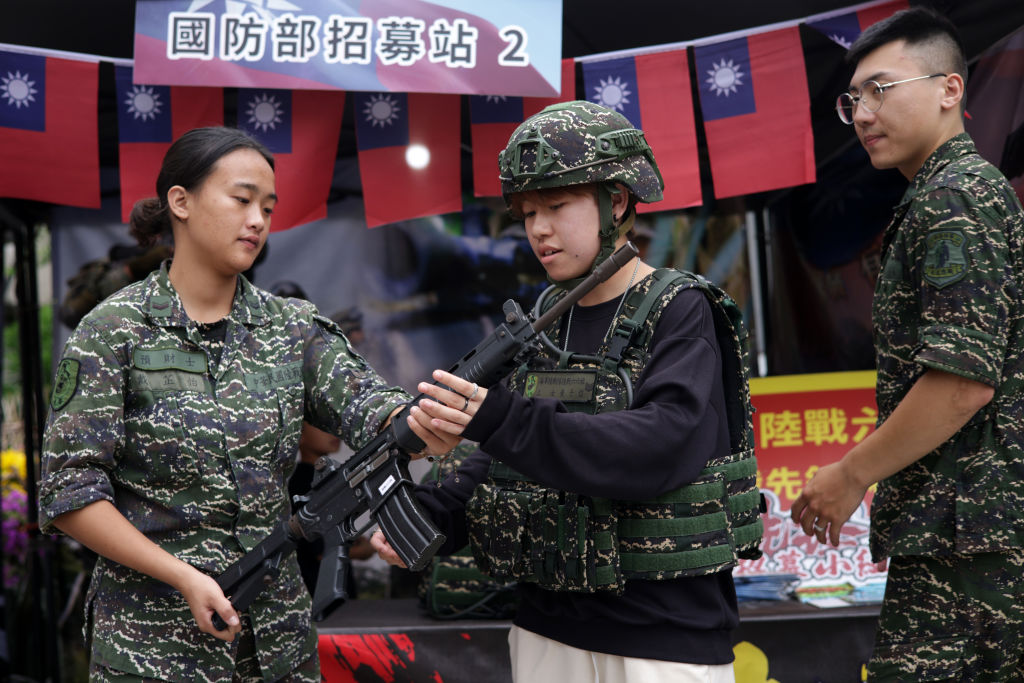 A visitor tries military outfit and holds a rifle at an Army recruiting booth at a pre-National Day street fair, on October 09, 2023 in New Taipei City, Taiwan.