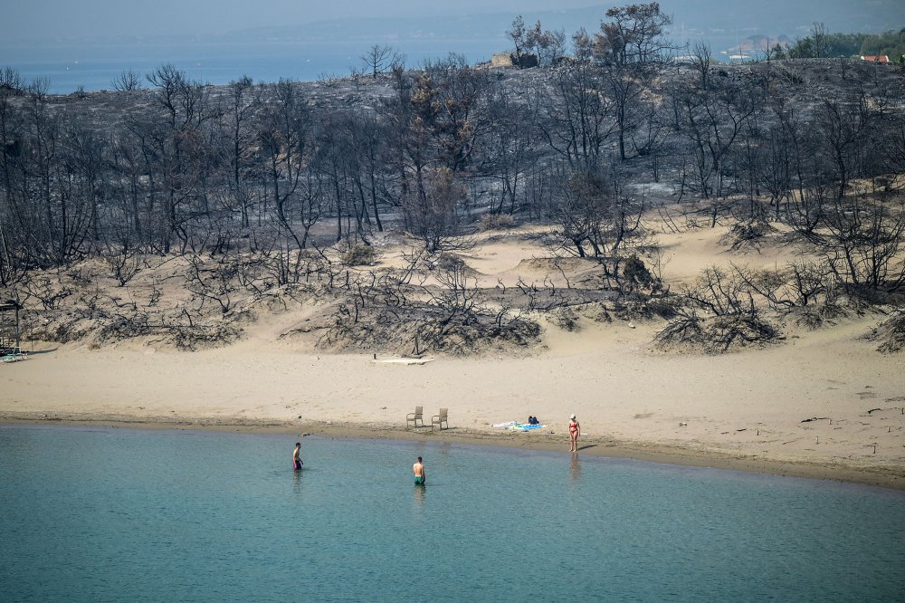 A woman enters the sea from a beach where wildfires destroyed the woods, at Glystra near the village of Gennadi in the southern part of the Greek island of Rhodes, on July 27.