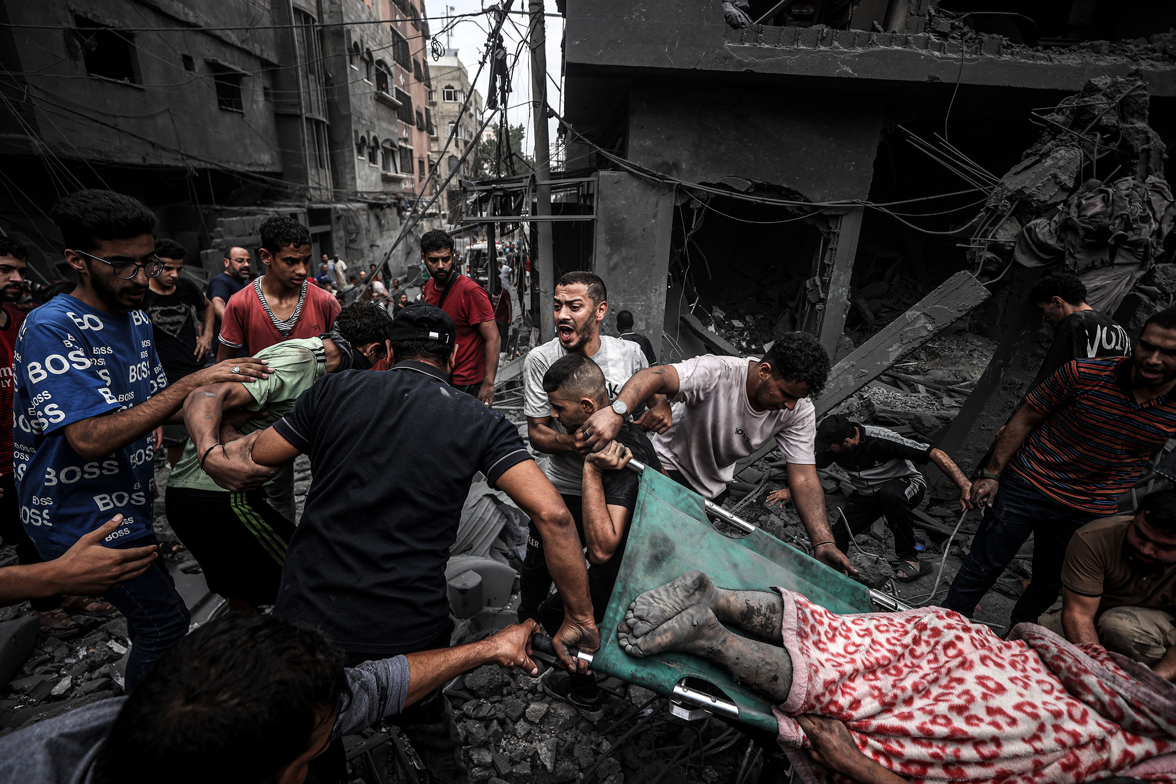 People carry injured and dead Palestinians from the rubbles of buildings as civil defense teams and civilians conduct search and rescue operations after Israeli attacks on Al-Shati refugee camp in Gaza City, on Oct. 27.