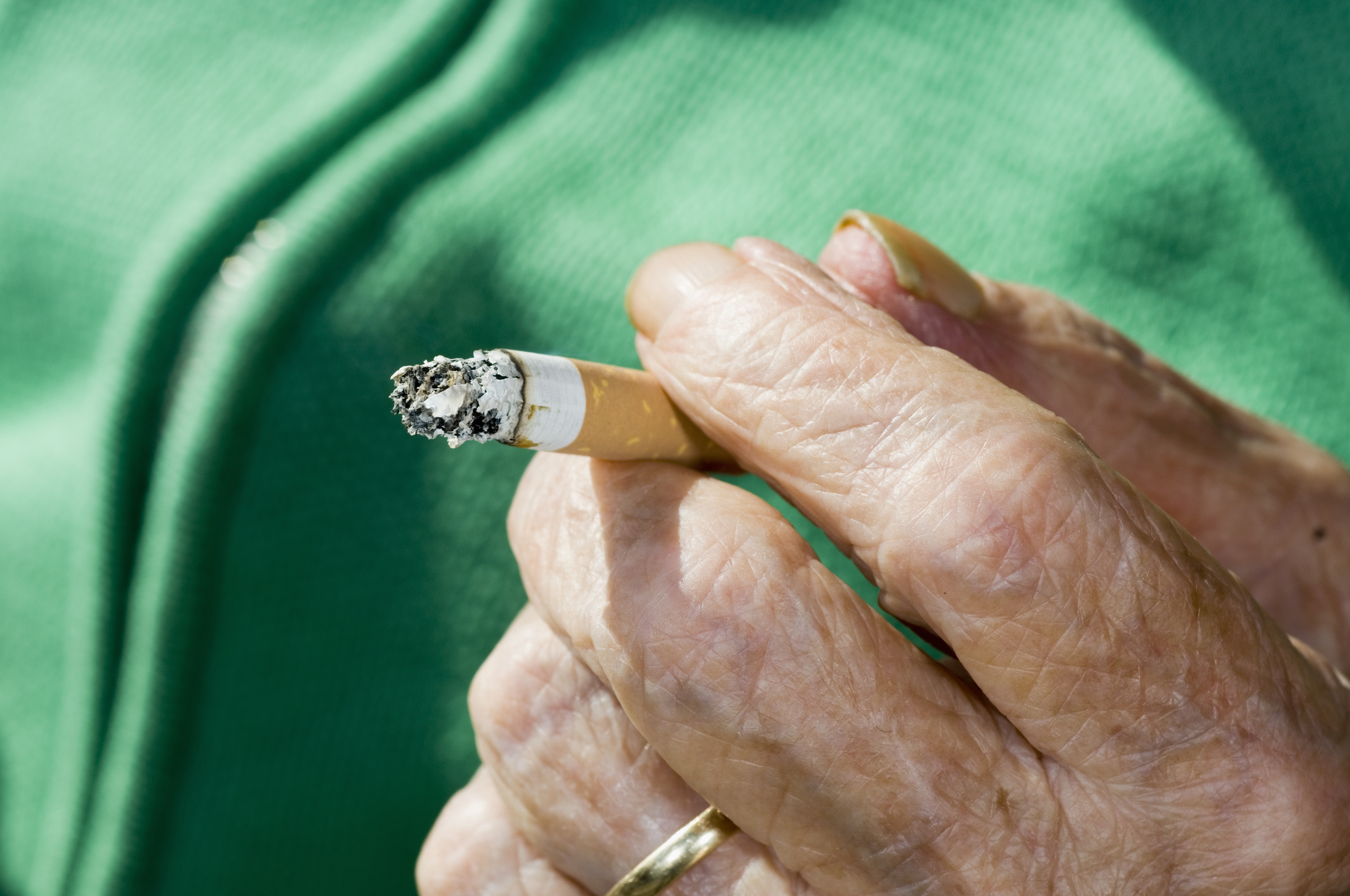 Elderly Hand Holding Cigarette Butt