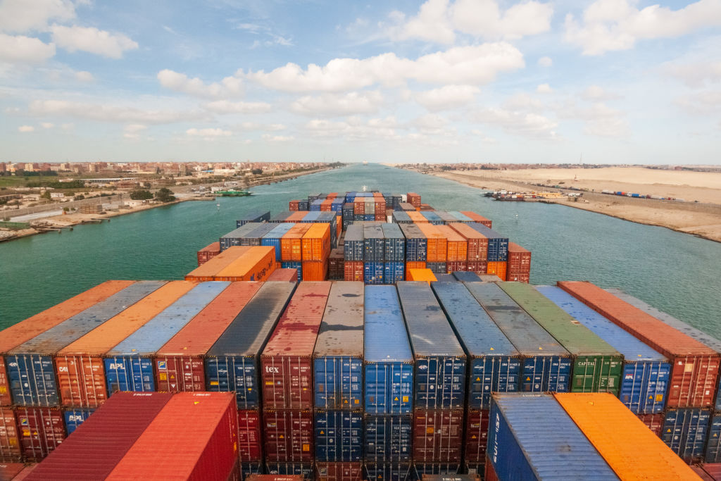 Loaded containers stacked on top of a cargo ship sailing in a canal, Suez Canal, Red sea, Egypt