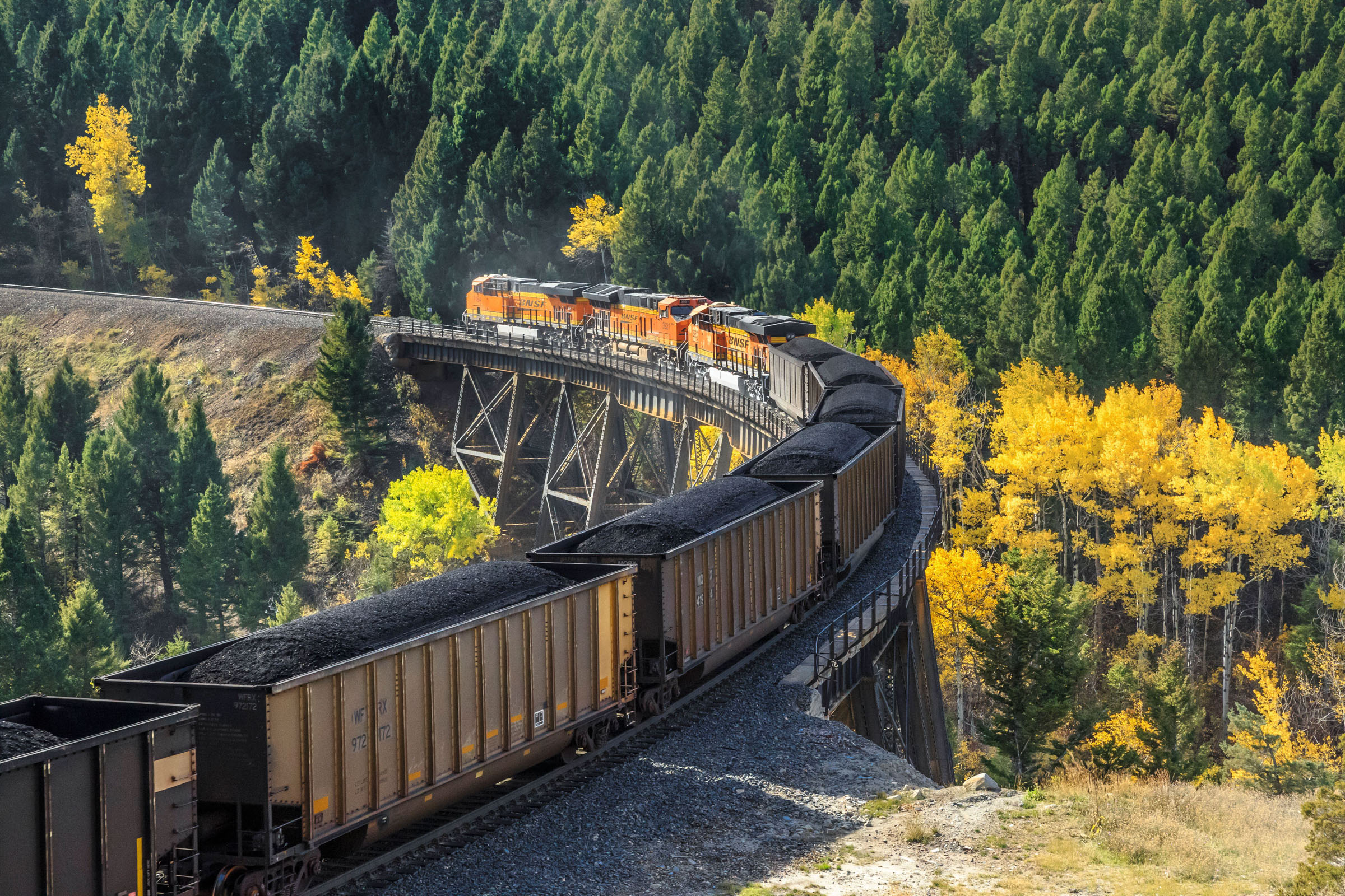 train passing over a high trestle below mullan pass in autumn near austin, montana