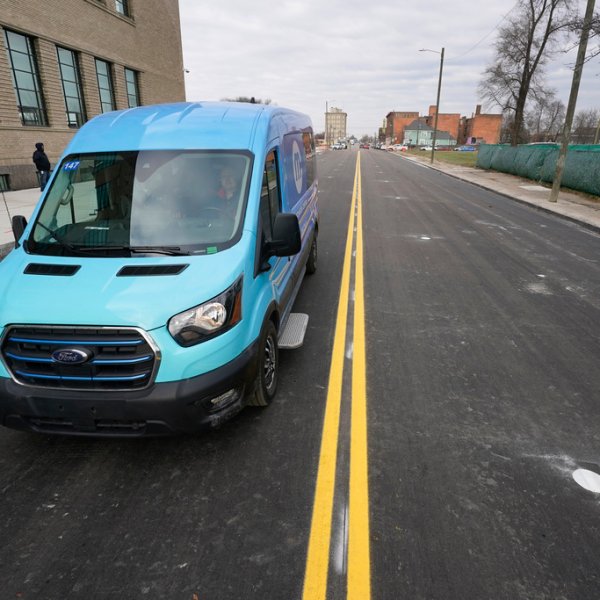 An electric van drives on a street with in-road wireless charging coils below the surface in Detroit, Nov. 29, 2023.