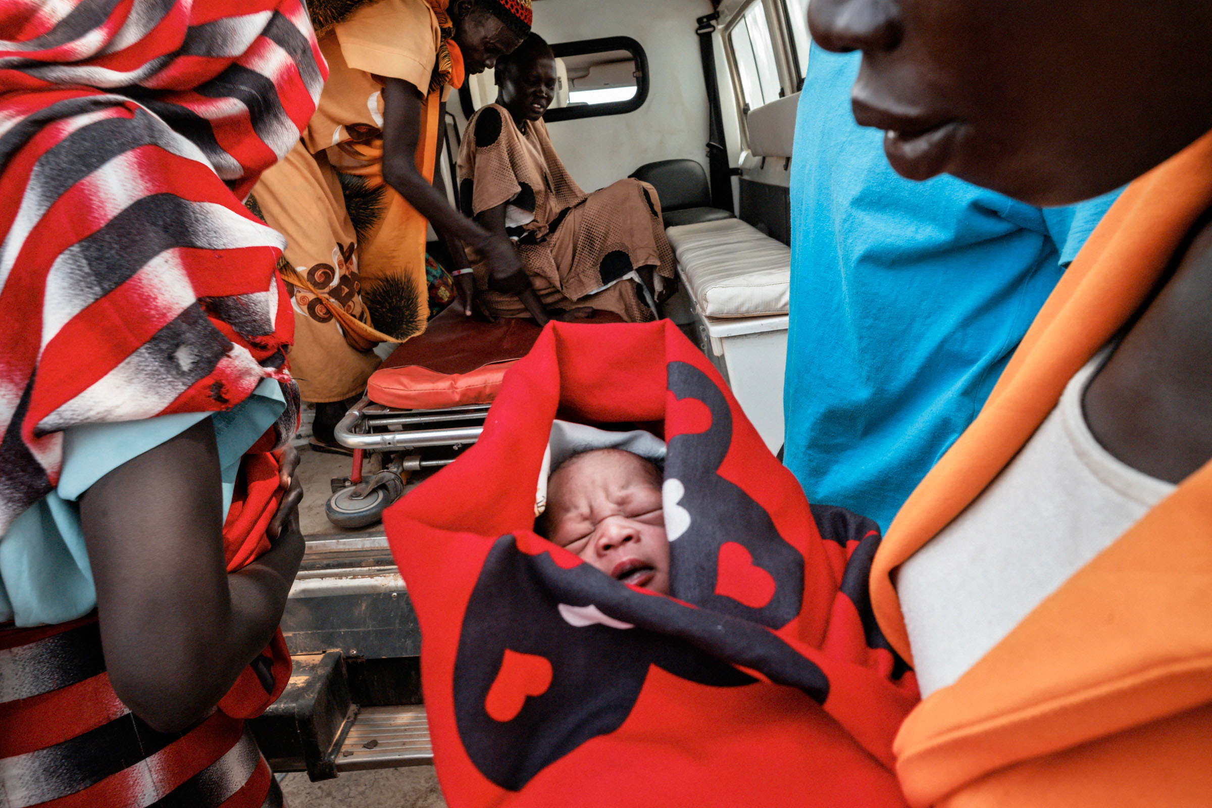 Mother holds a newly born child in an ambulance outside the Gongoi IDP camp.