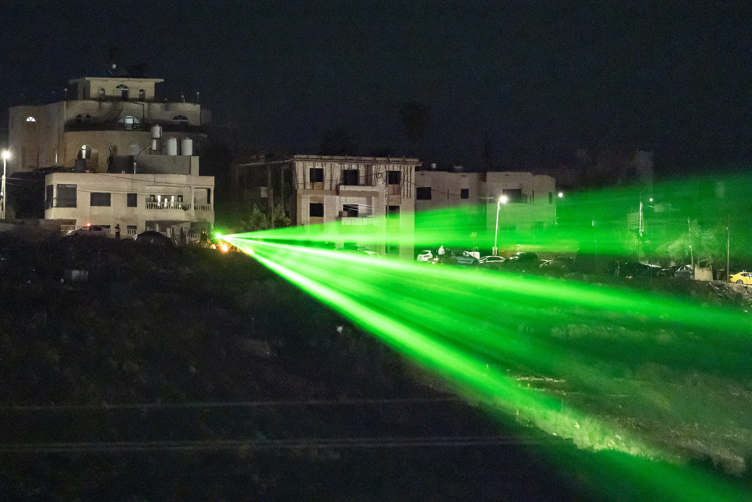 Palestinians direct a laser toward the Ofer military prison located between Ramallah and Beitunia in the occupied West Bank on Nov. 30, 2023, before the release of Palestinian prisoners in exchange for hostages held by Hamas in Gaza.