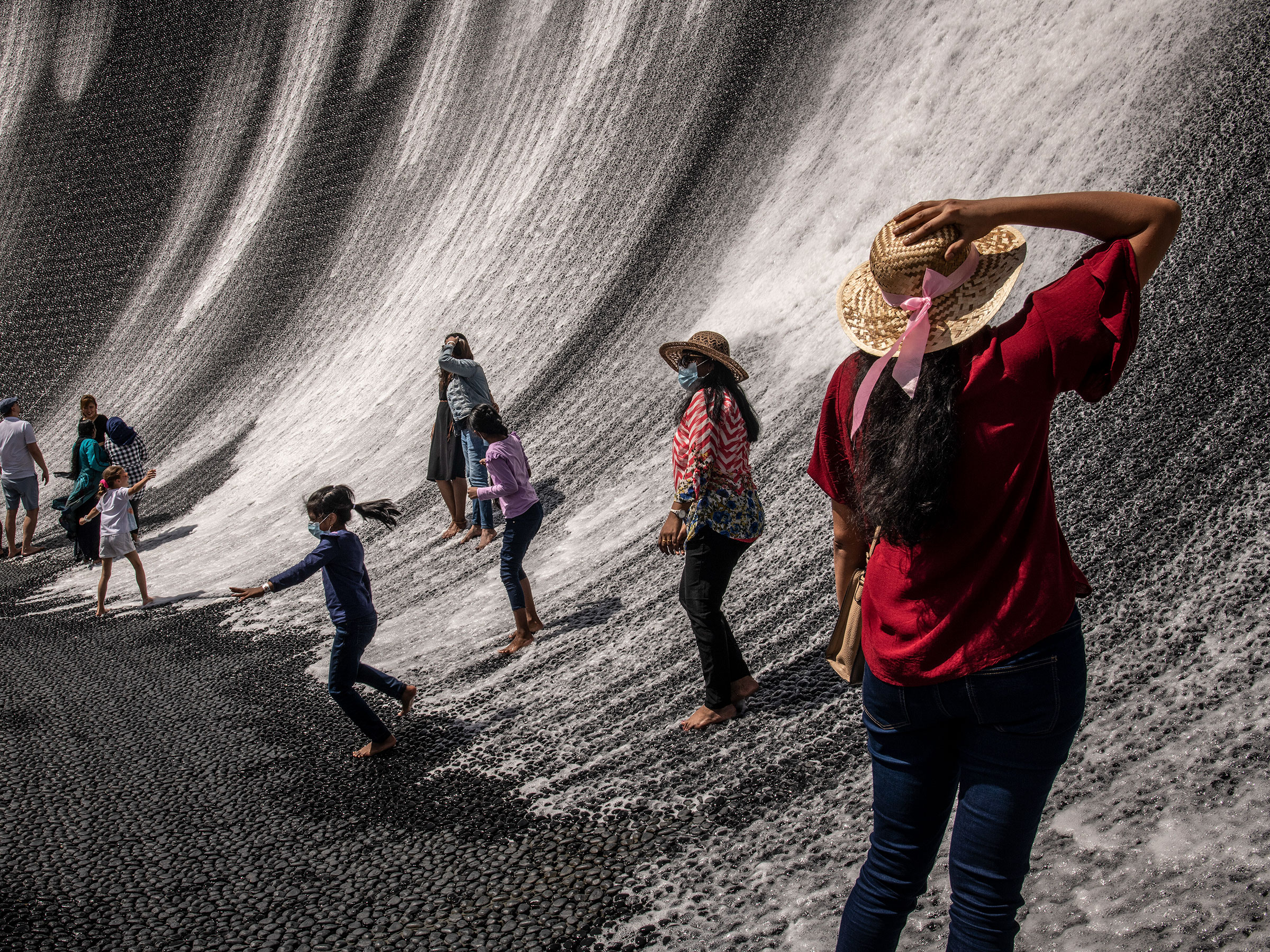Visitors at the "Surreal" water attraction, featuring a 360-degree, 14-meter-high wall of cascading water, in Dubai, March 2022.