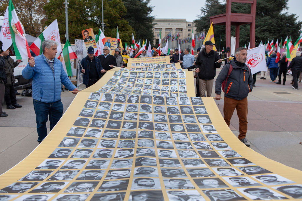 Protesters carry a banner with portraits of the people
