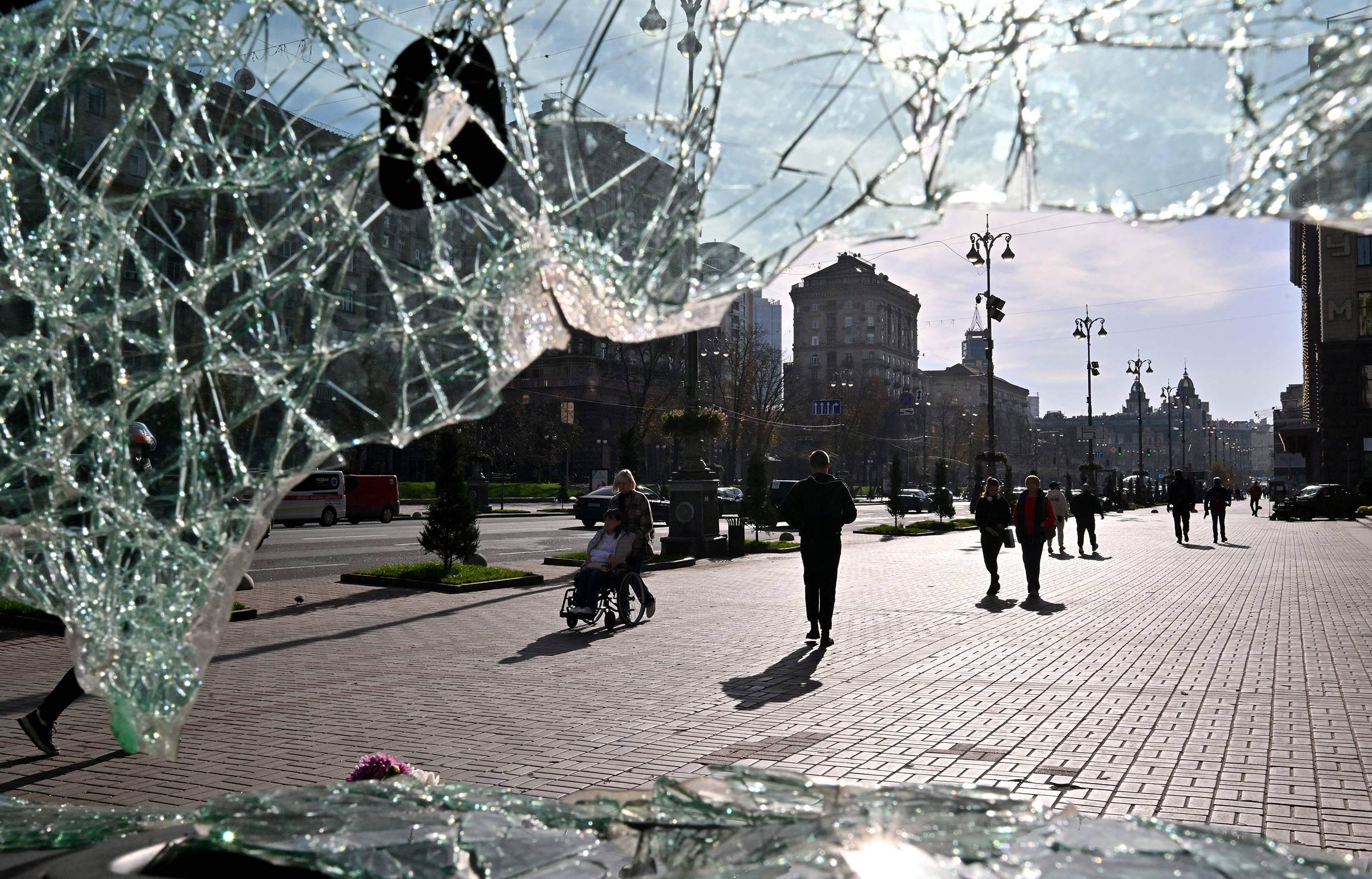 A view of daily life in Kyiv taken through the broken windshield of a vehicle destroyed on the frontline and displayed in an exhibit in the city center, Oct. 31, 2023. (Sergei Supinsky—AFP/Getty Images)