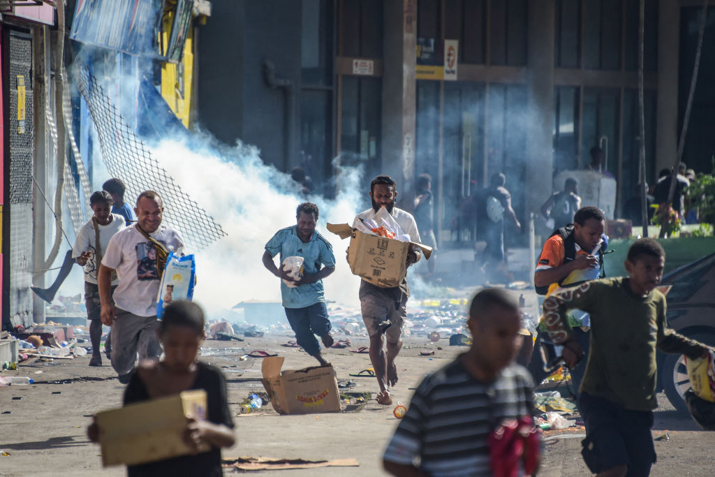 People run with merchandise as crowds leave shops with looted goods amid a state of unrest in Port Moresby on Jan. 10, 2024.