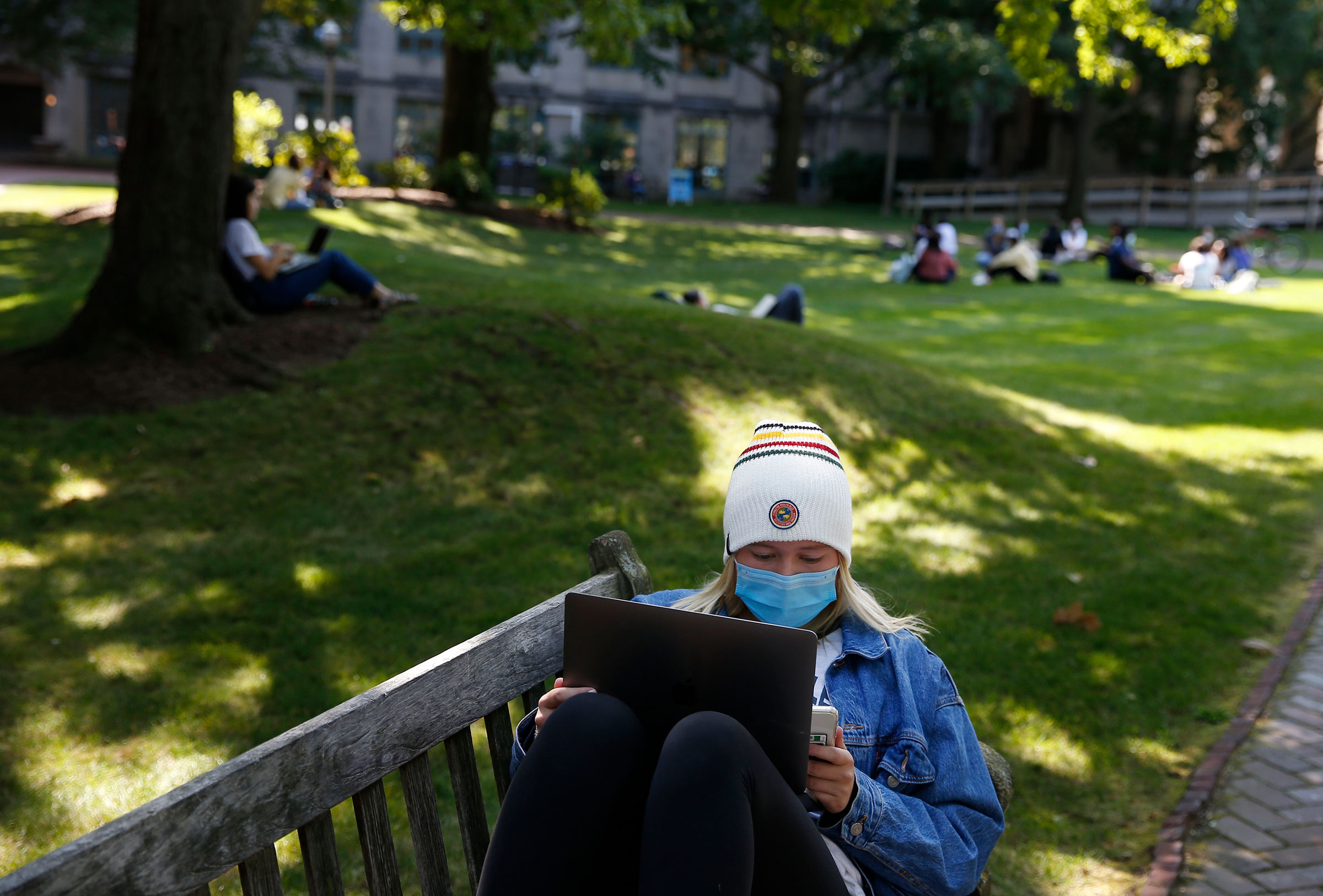 A student wears a mask to protect against the spread of COVID-19 as she worked on her laptop outside at Boston University, on Sept. 23, 2020.