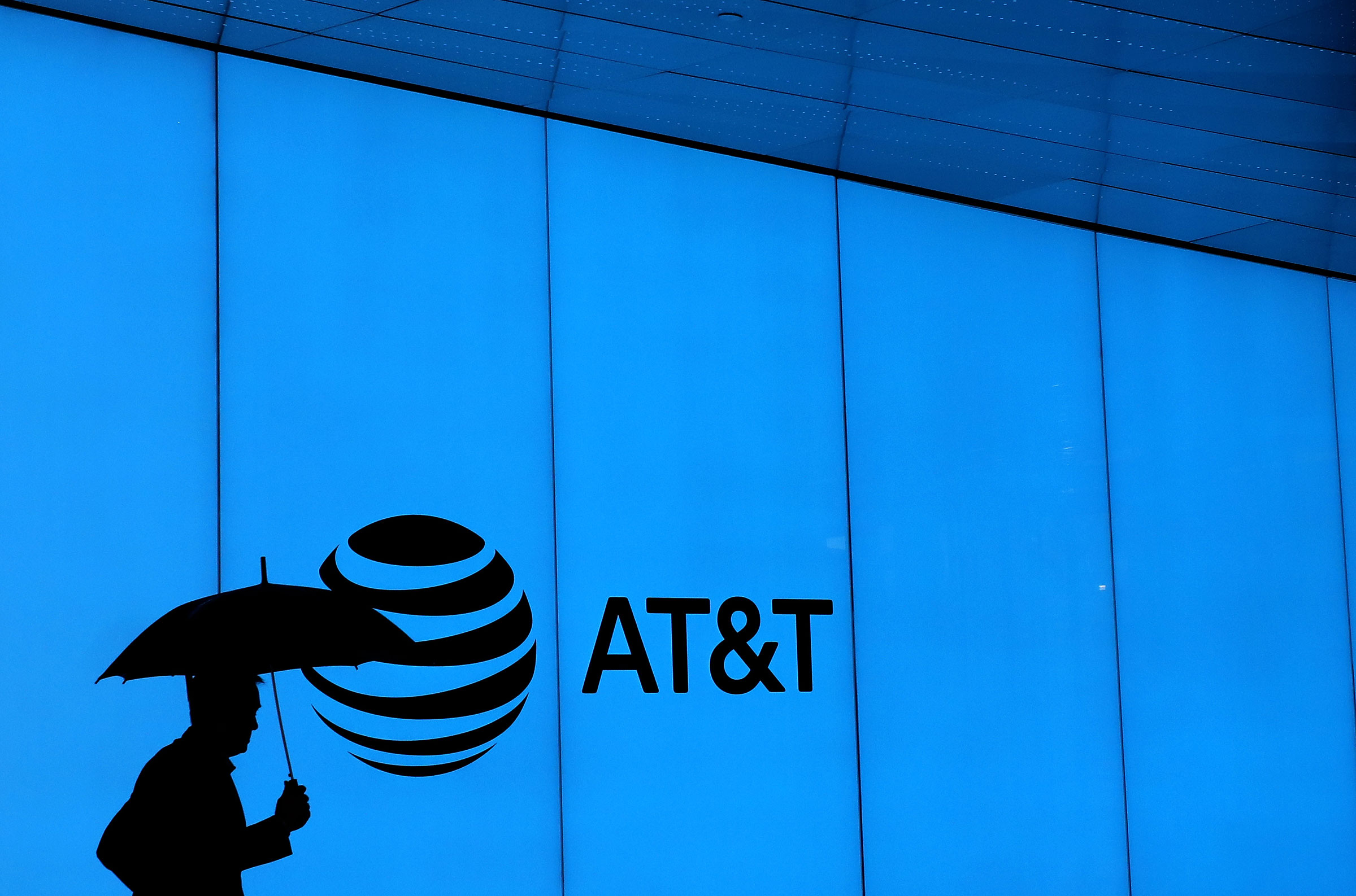 silhouette of a man holding umbrella against blue wall with AT&T logo