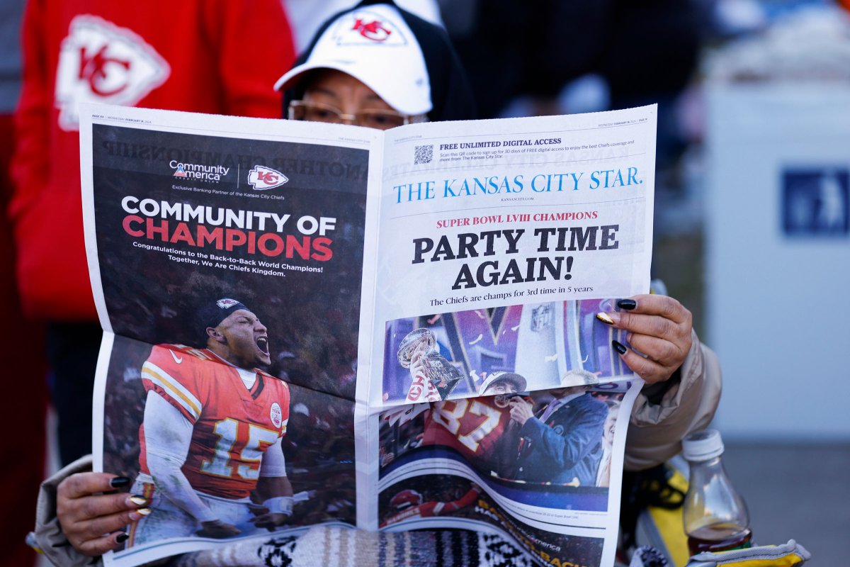 A fan reads a local newspaper during the parade.