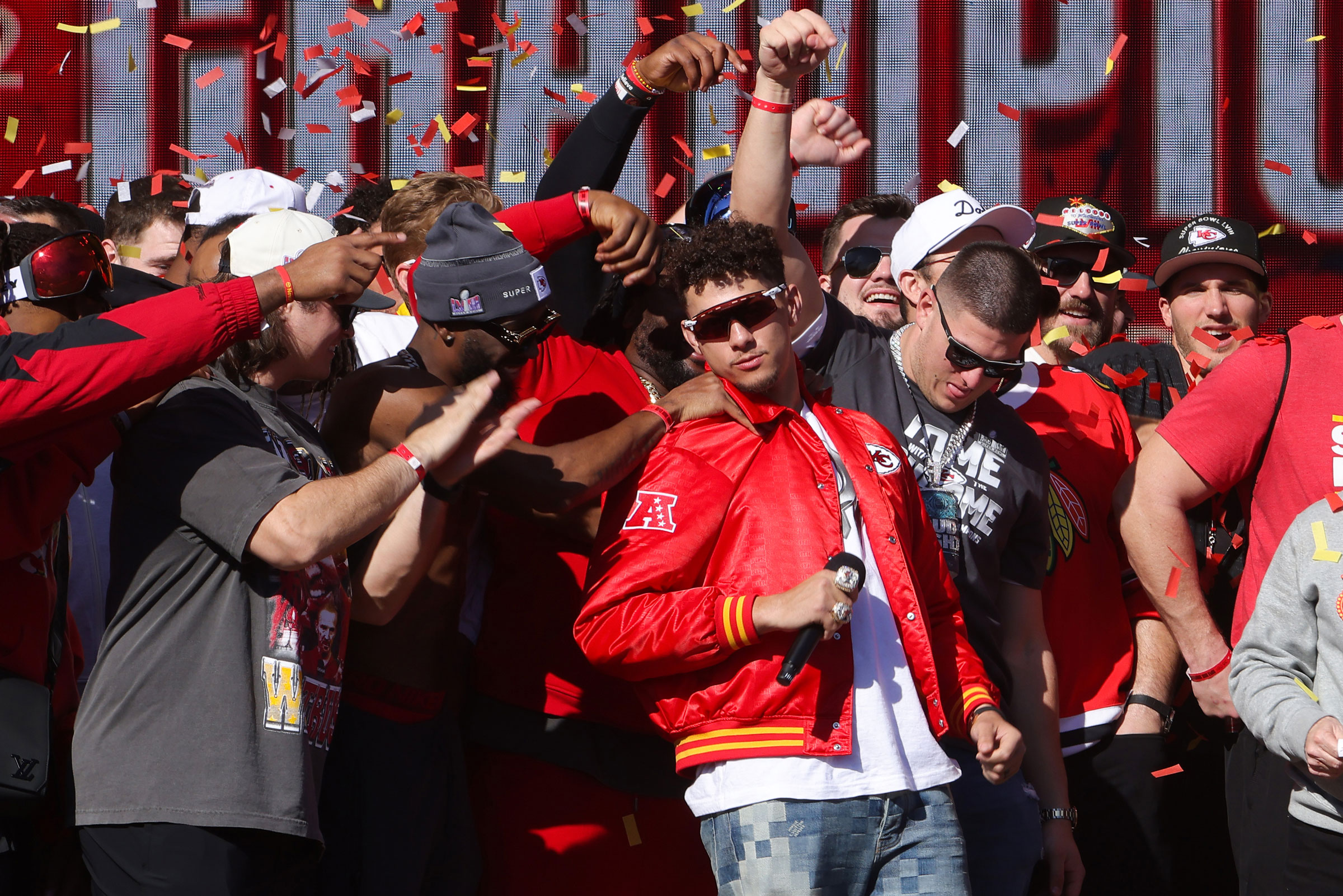 Patrick Mahomes celebrates with teammates on stage during the Super Bowl victory parade.