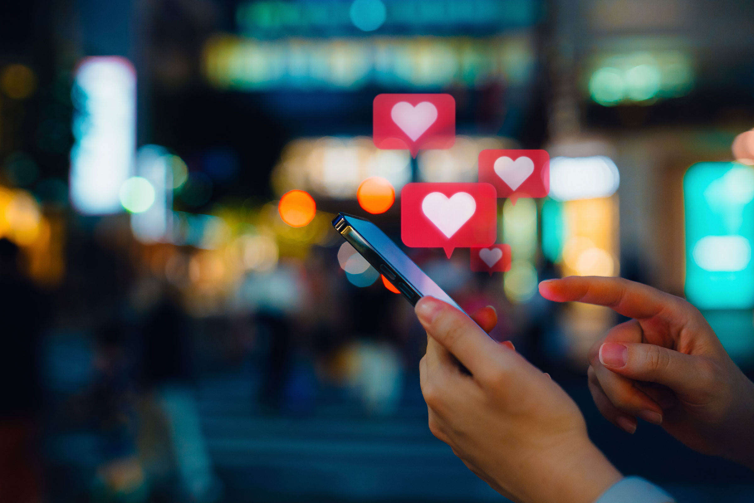 woman holding phone with digital emoji hearts